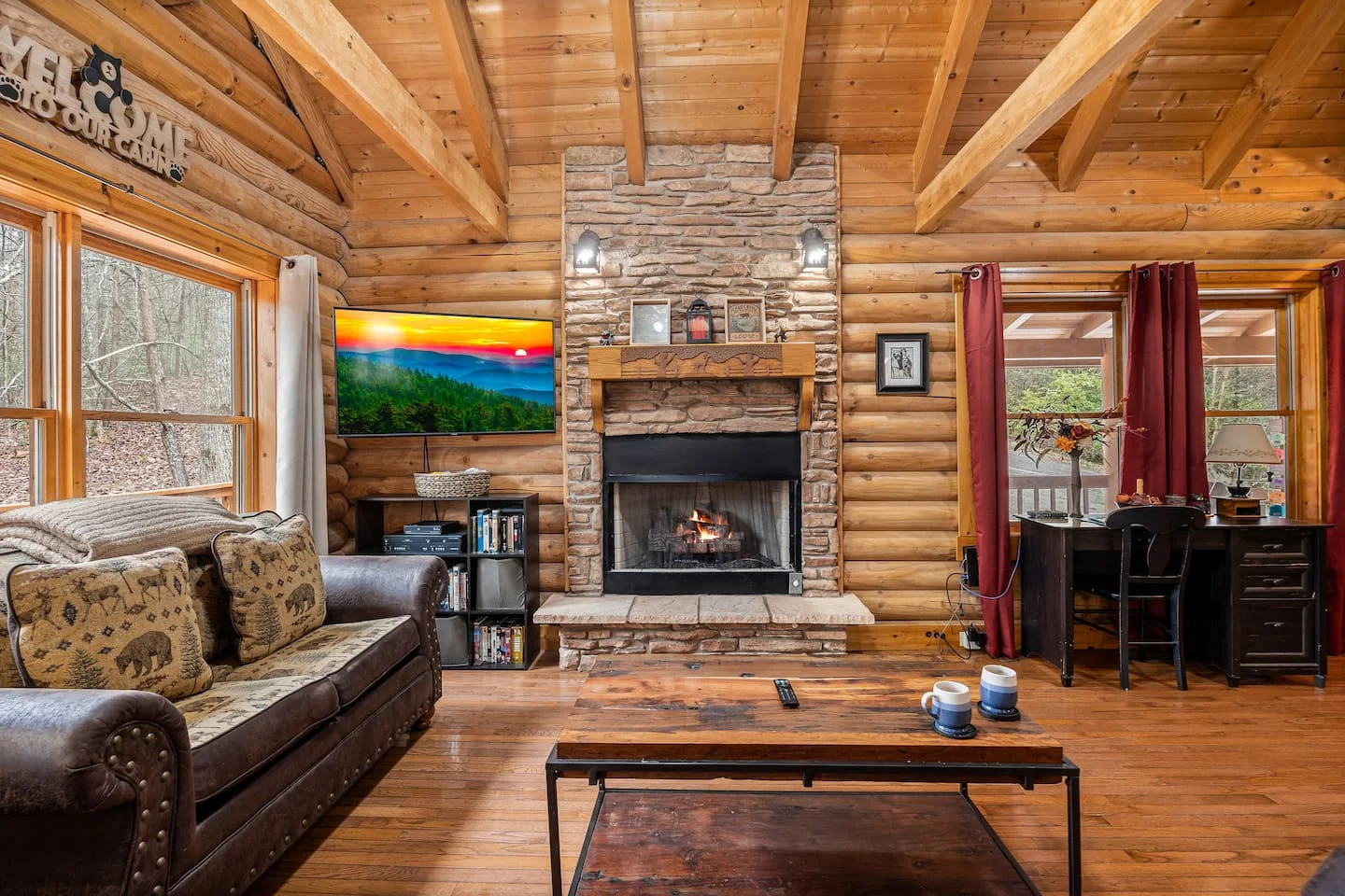Rustic log cabin living room with stone fireplace and forest views, perfect base for Laurel Falls hike in Gatlinburg