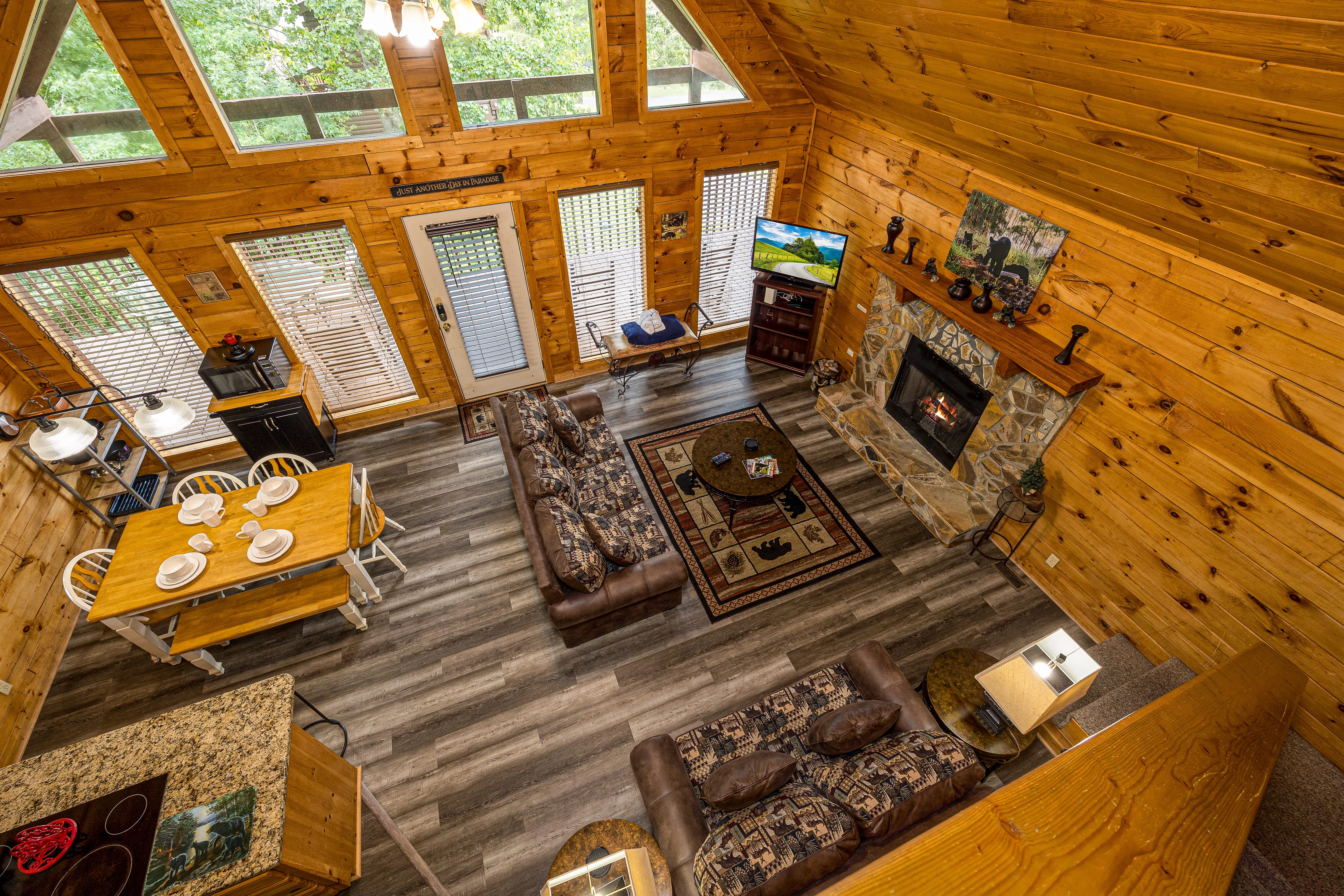 Spacious living room in a Pigeon Forge cabin with private pool featuring stone fireplace, skylights, and rustic knotty pine