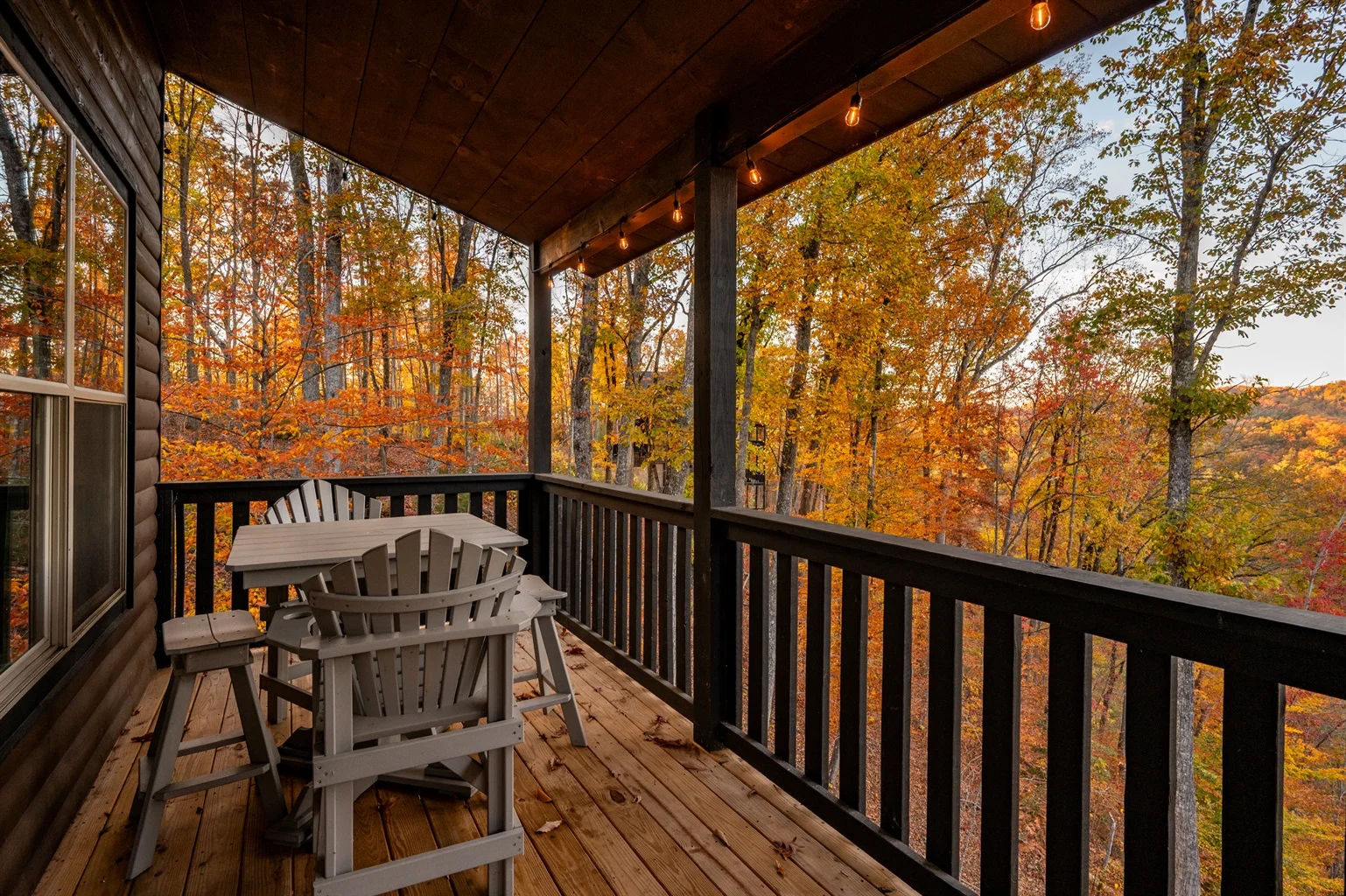 Covered deck with Adirondack chairs overlooking autumn forest, ideal base for Gatlinburg Trail hikes
