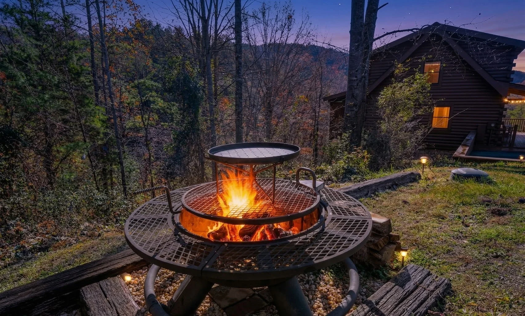 Two-tier fire pit with flames on wooden deck surrounded by Smoky Mountain forest and log cabin, showcasing outdoor amenities