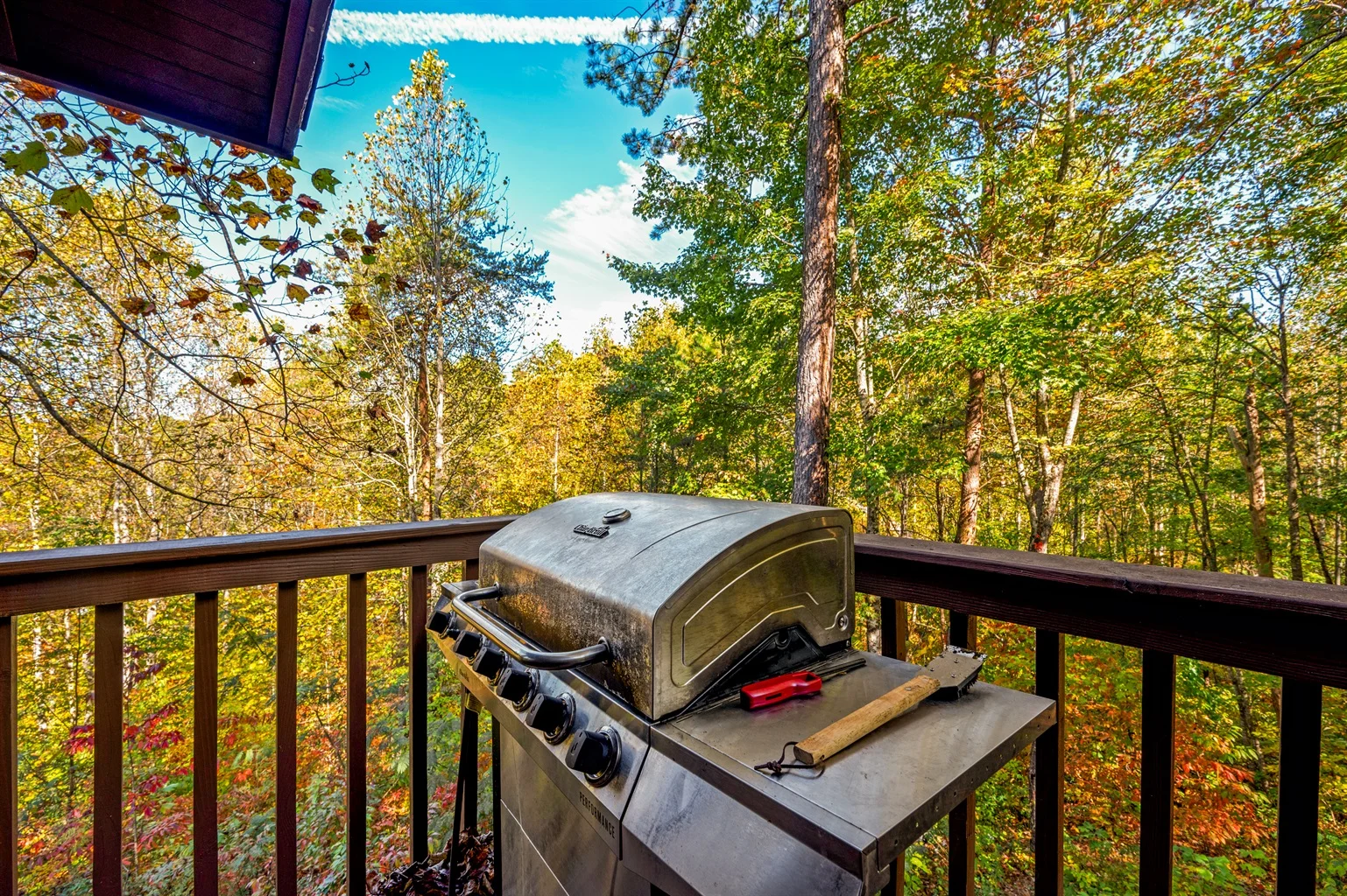 Gas grill on wooden deck overlooking autumn forest at Sevierville TN mountain cabin with gold and green foliage