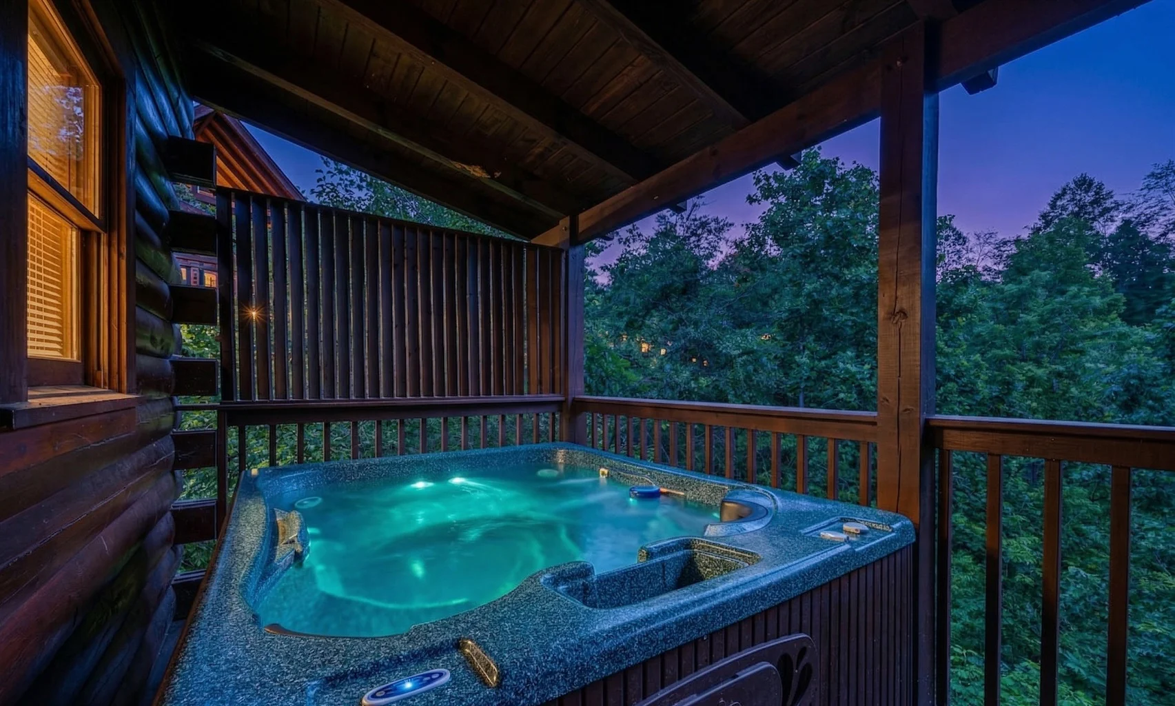 Private hot tub with turquoise jets on illuminated deck overlooking forest at Mountain Memories luxury mountain cabin