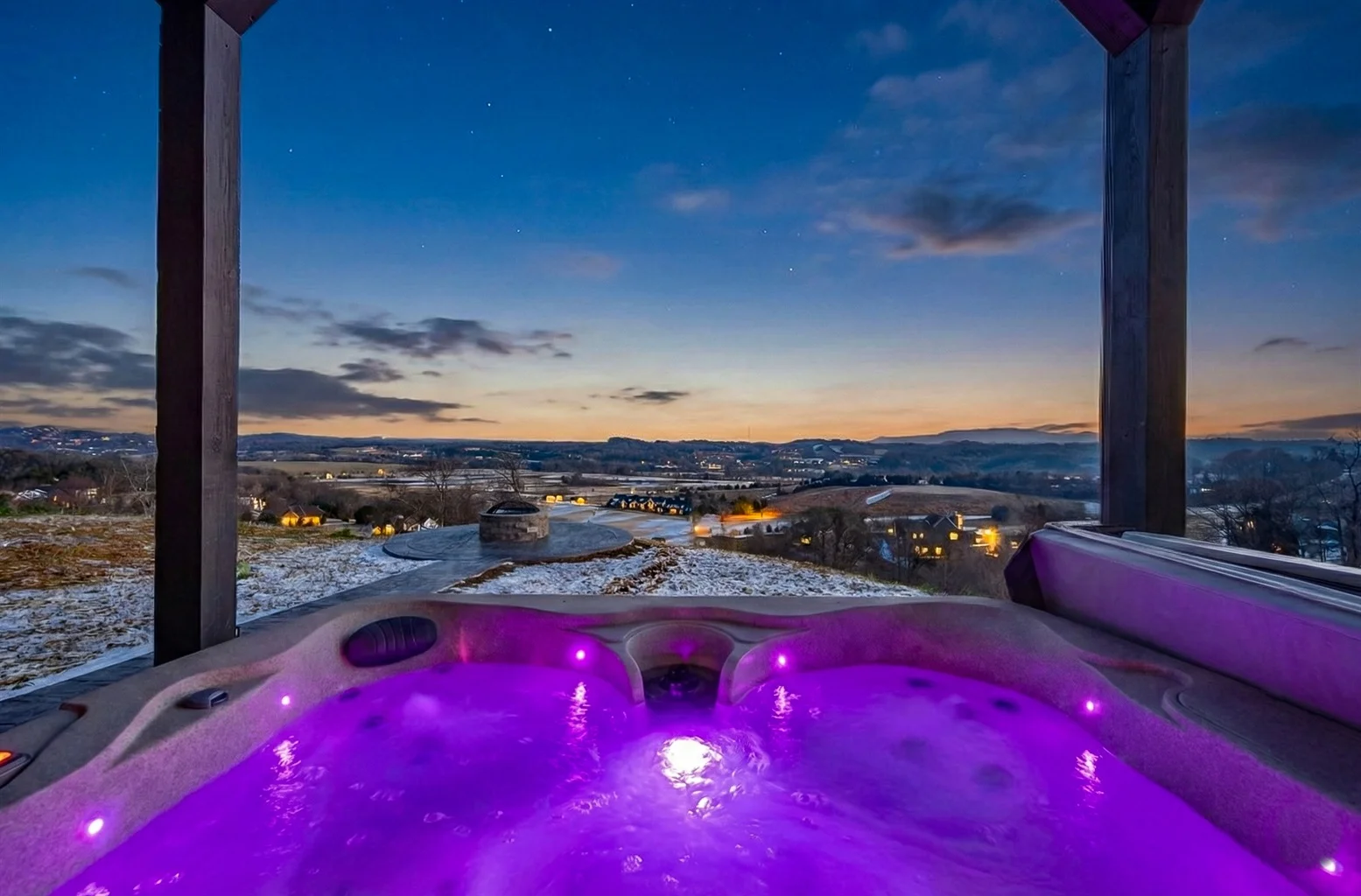 Luxury hot tub with purple LED lighting on deck overlooking mountain valley at dusk in Sevierville