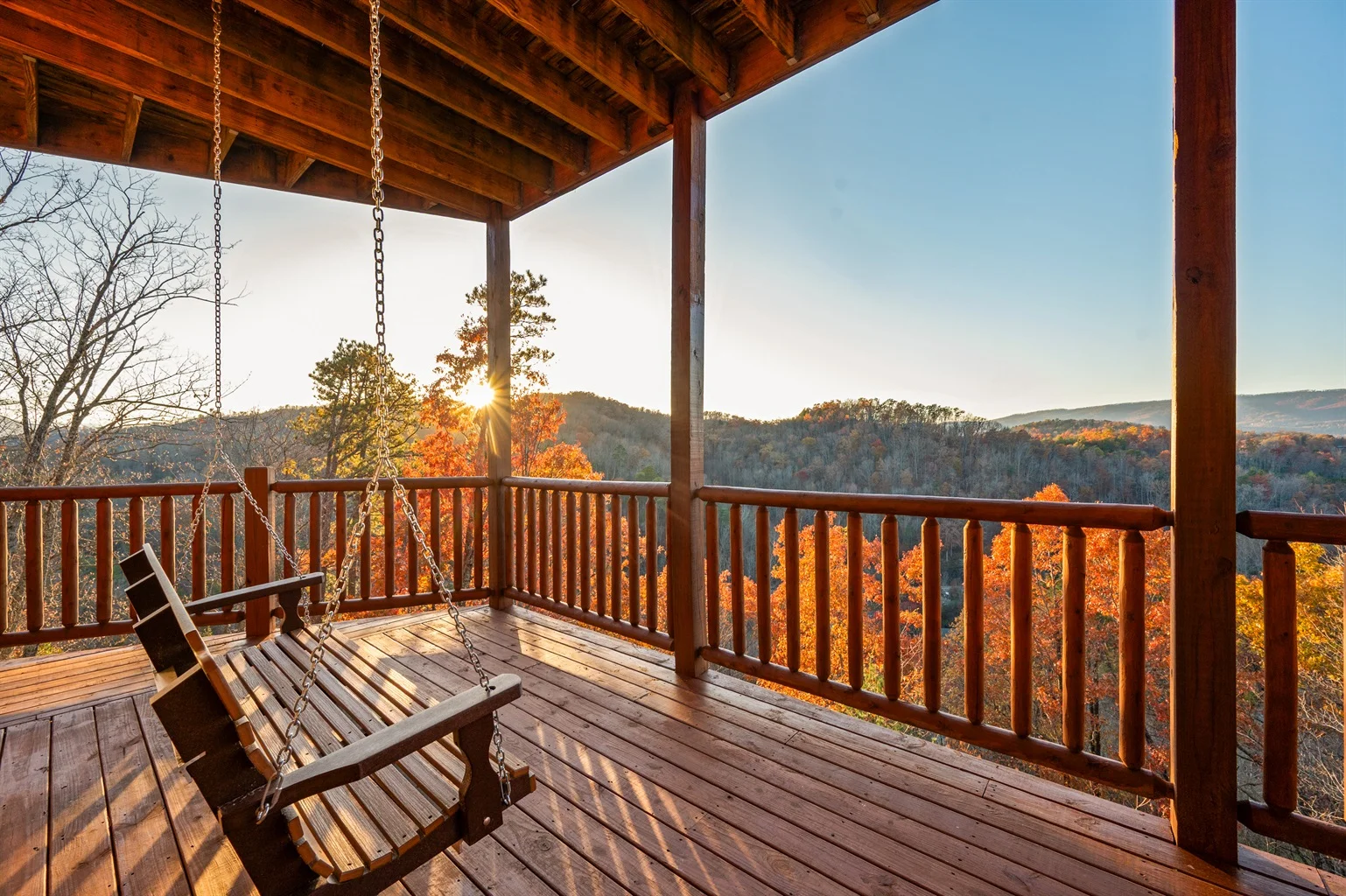 Spacious mountain cabin patio with wooden rocking chairs, composite decking, and forest views ideal for vacation rental