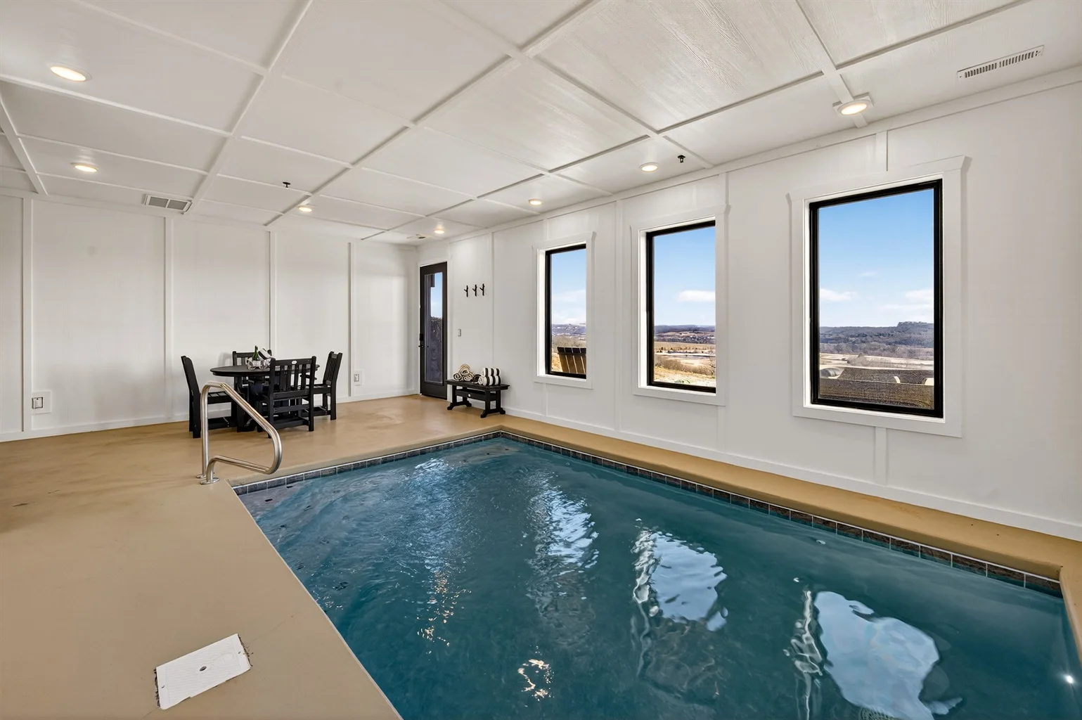 Indoor heated swimming pool at Pigeon Forge cabin with private pool, featuring turquoise water, wooden deck, and scenic