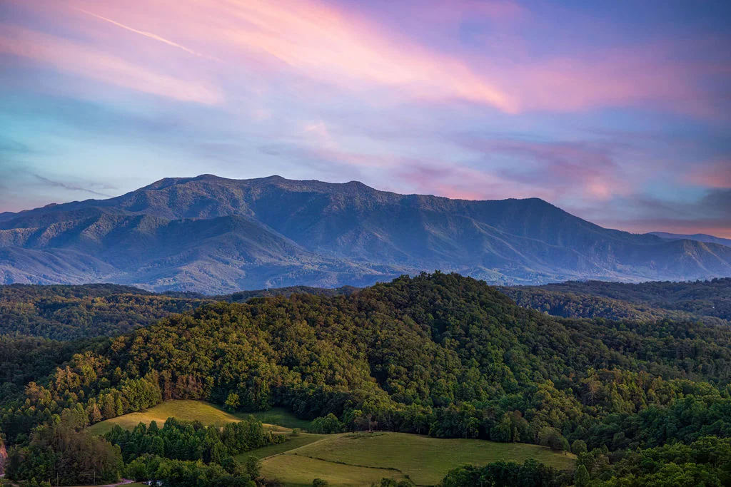 Smoky Mountains scenic vista at sunrise with layered ridges and forested valleys in shades of blue and purple near