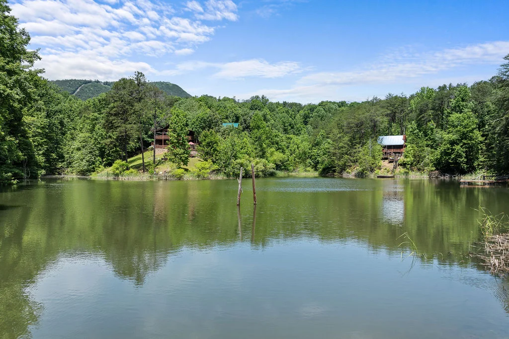 Serene riverfront view with cabin structures on forested banks near historic homestead ruins along Gatlinburg Trail in Great