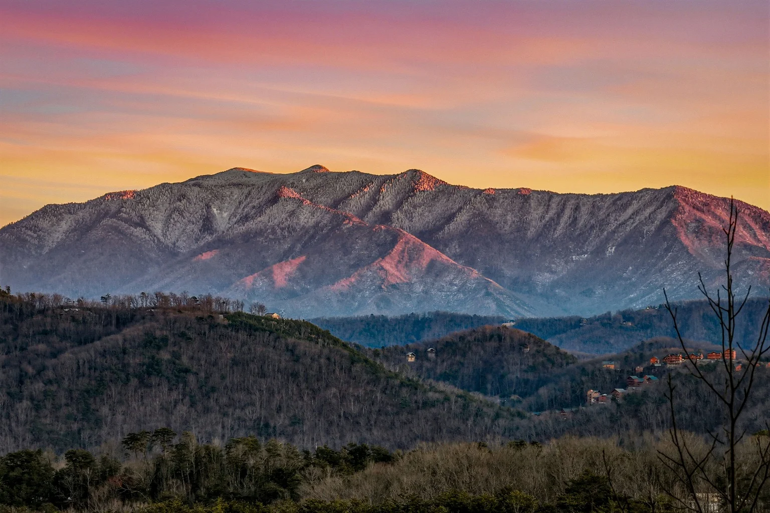 Panoramic sunset view of rolling Smoky Mountains with golden light illuminating forested ridges, showcasing the scenic