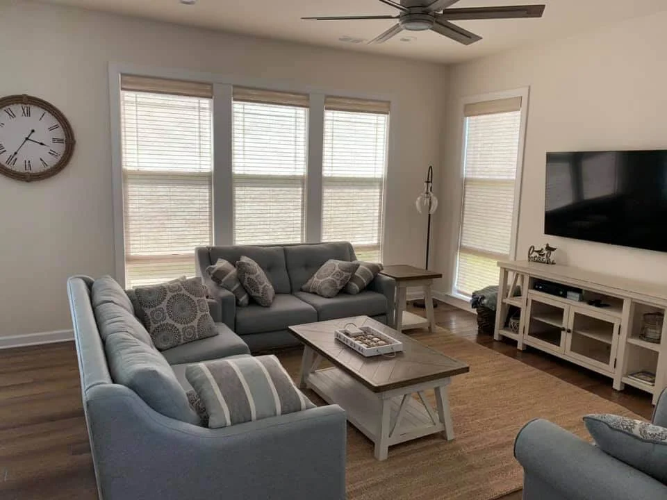 Bright living room with white blinds covering large windows, demonstrating quality blinds repair services in Annapolis, MD