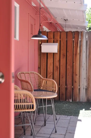 Modern dog-friendly restaurant patio with rattan bar stools and pink wall in downtown Palm Springs