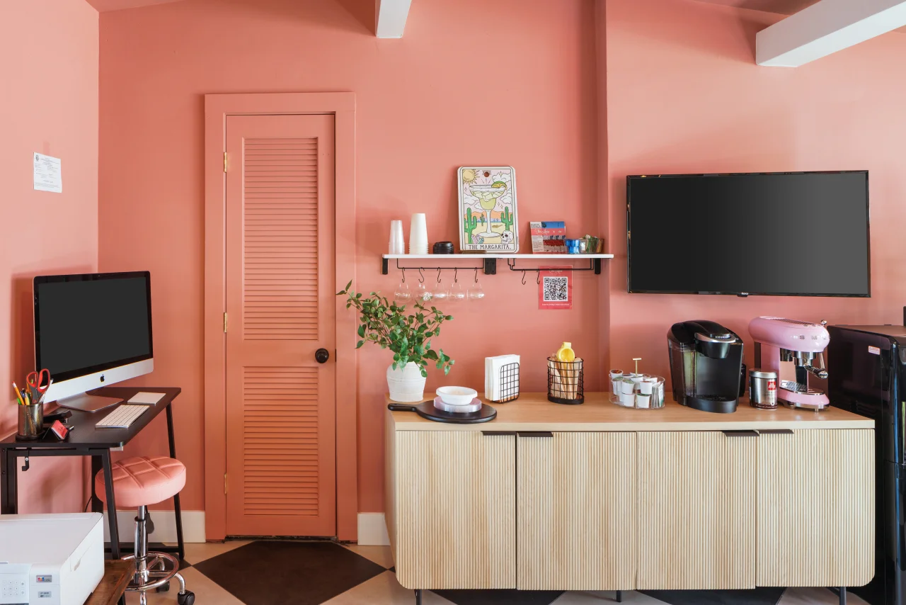 Modern workspace in The Edie Suite at a Palm Springs mid-century modern hotel featuring coral pink walls, iMac desk, and