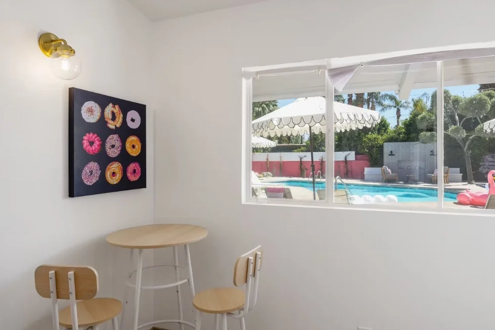 Modern dining area in The Barbie Suite with pool view, wooden chairs, and pop art decor creating a sophisticated Palm Desert