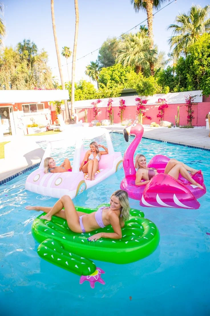 Guests enjoy colorful floats in the turquoise pool at this boutique hotel Palm Springs with pink mid-century modern