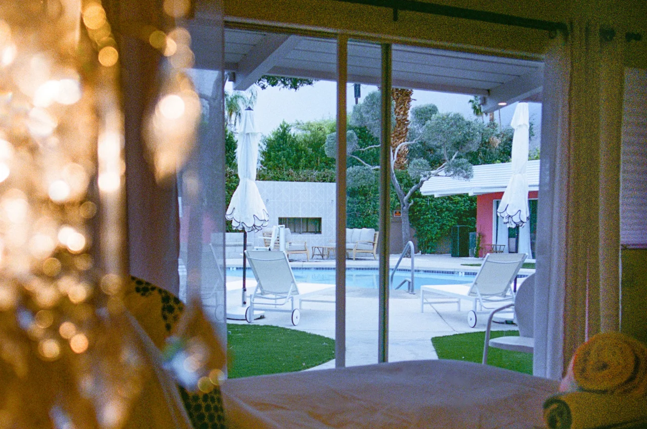 The Kate Suite's floor-to-ceiling glass doors reveal a resort pool and patio, showing the type of accommodations visitors