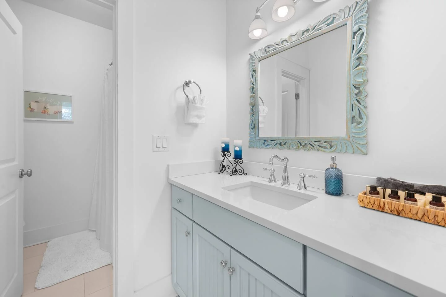 Modern bathroom with coastal decor, pale blue vanity, and turquoise mirror in St. Augustine vacation rental