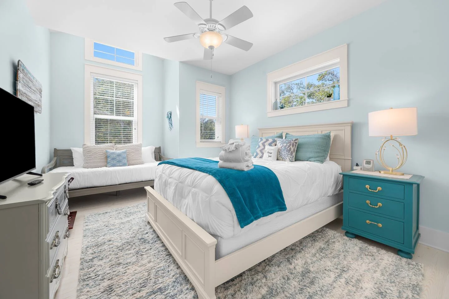 Professional vacation rental turnover service setting up bright beachside bedroom with white linens and coastal decor in St.