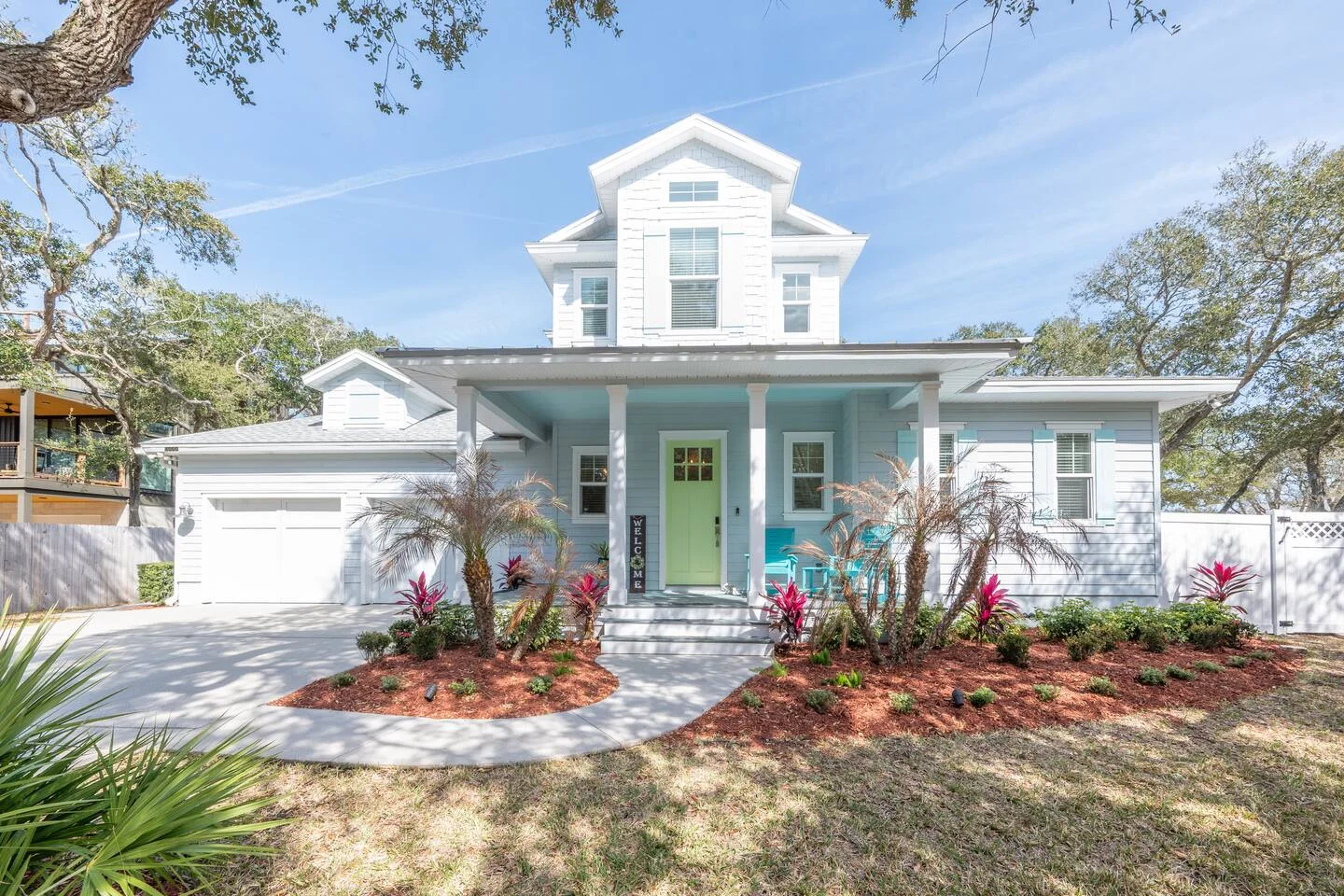 White farmhouse with lime-green door and tropical landscaping in St. Augustine vacation rental