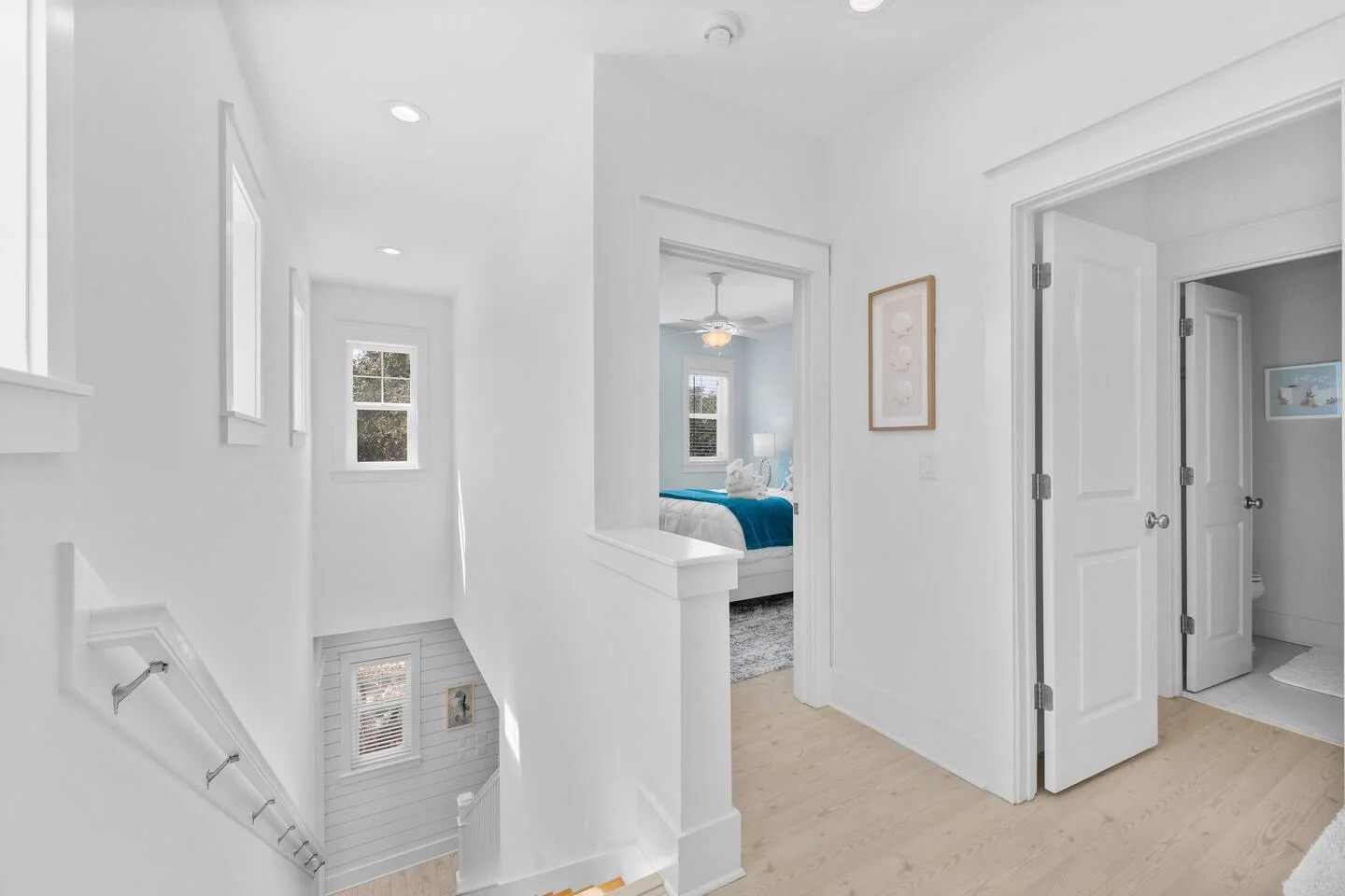 Modern hallway with white walls and light wood flooring leading to turquoise accent bed, St. Augustine vacation rental
