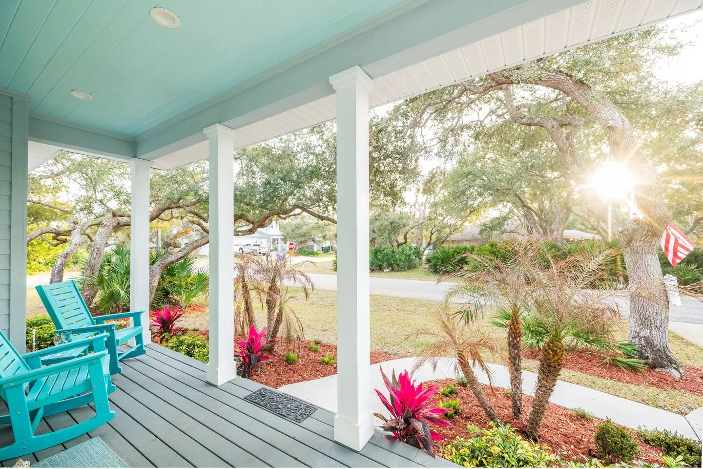 Covered porch with turquoise ceiling and Adirondack chairs overlooking tropical landscape in St Augustine vacation rental