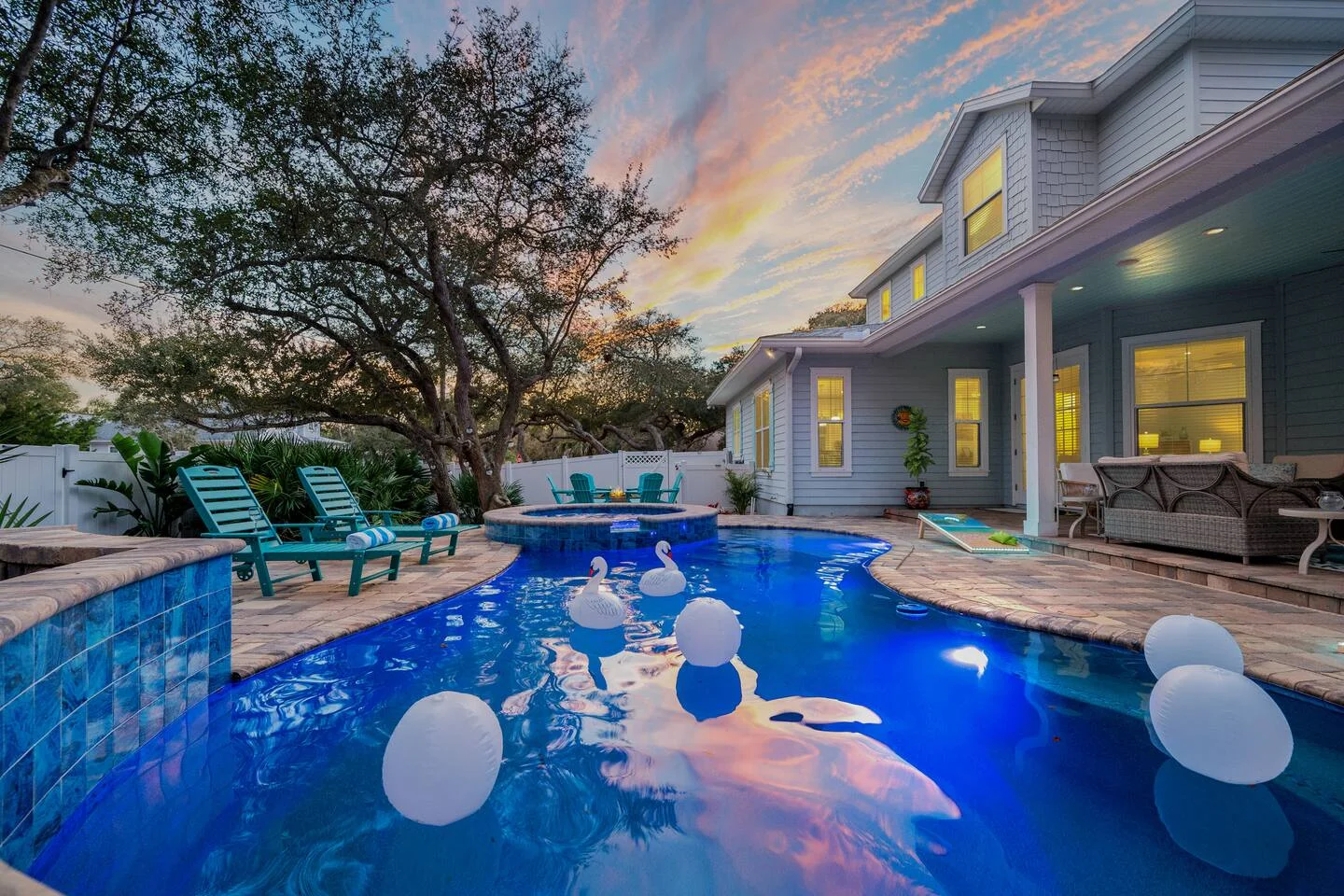 Luxury resort-style pool with swan floats and hot tub at sunset in St Augustine vacation rental