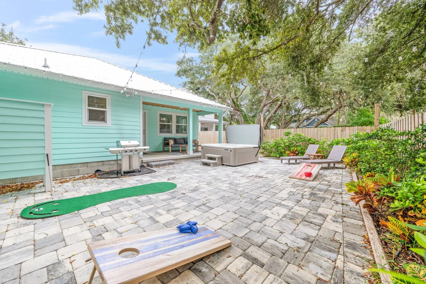 Turquoise cottage backyard with patio, hot tub, and entertainment area showing what property management costs cover in St.