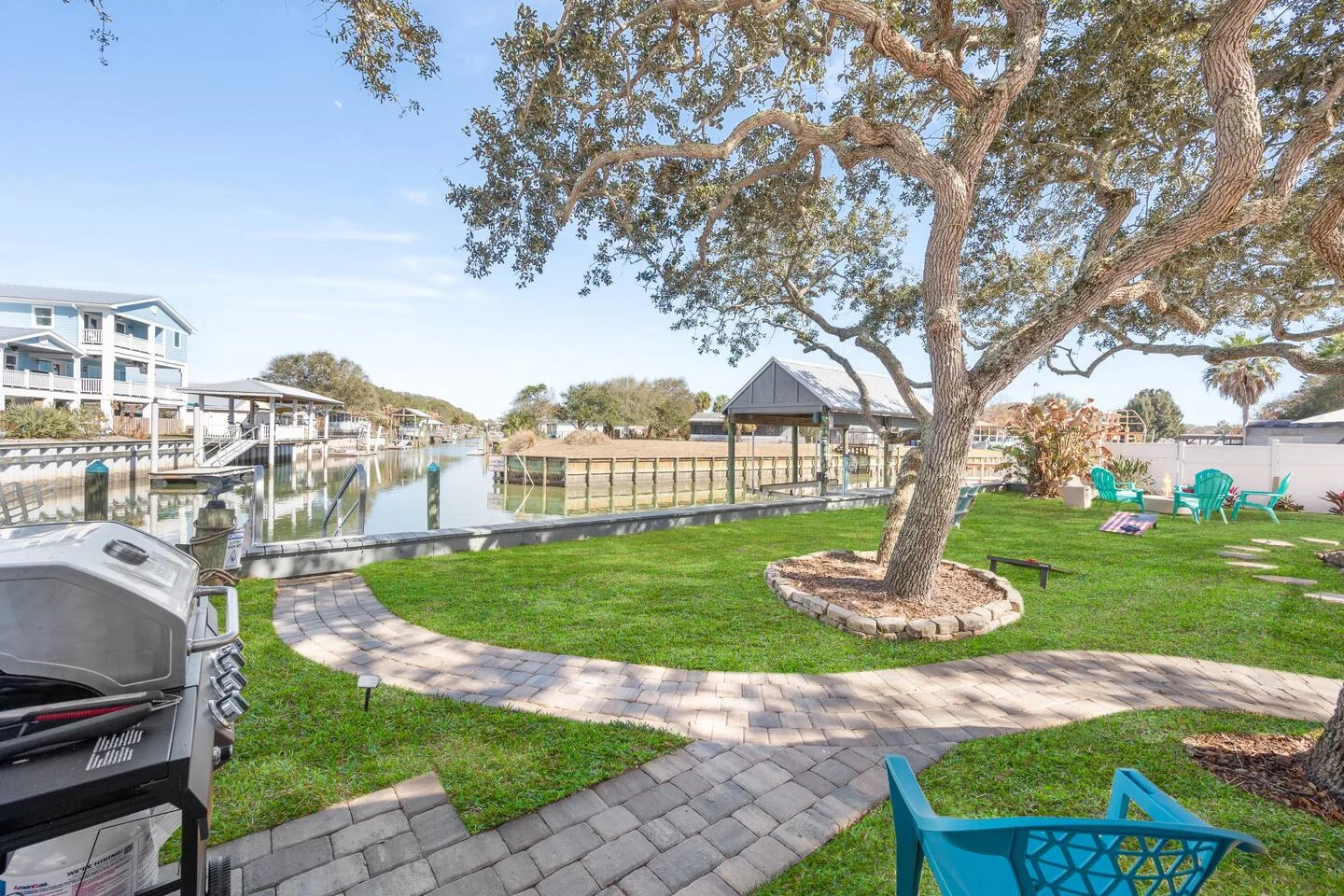 Waterfront backyard with green lawn and oak tree, showing why property managers in St. Augustine love managing premium
