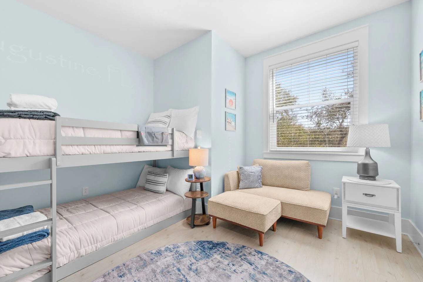 Bright guest bedroom with bunk beds and beige seating showcasing warm minimalism vacation rental design at Vilano Beach