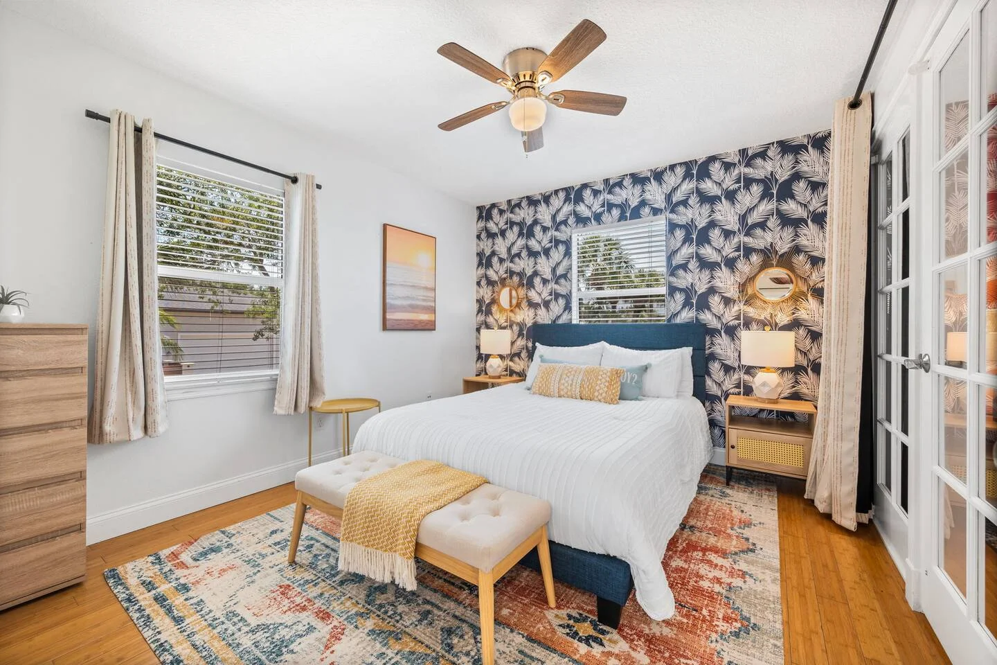 Master bedroom at Driftwood St. Augustine vacation rental with queen bed, navy palm leaf wallpaper, and natural light from