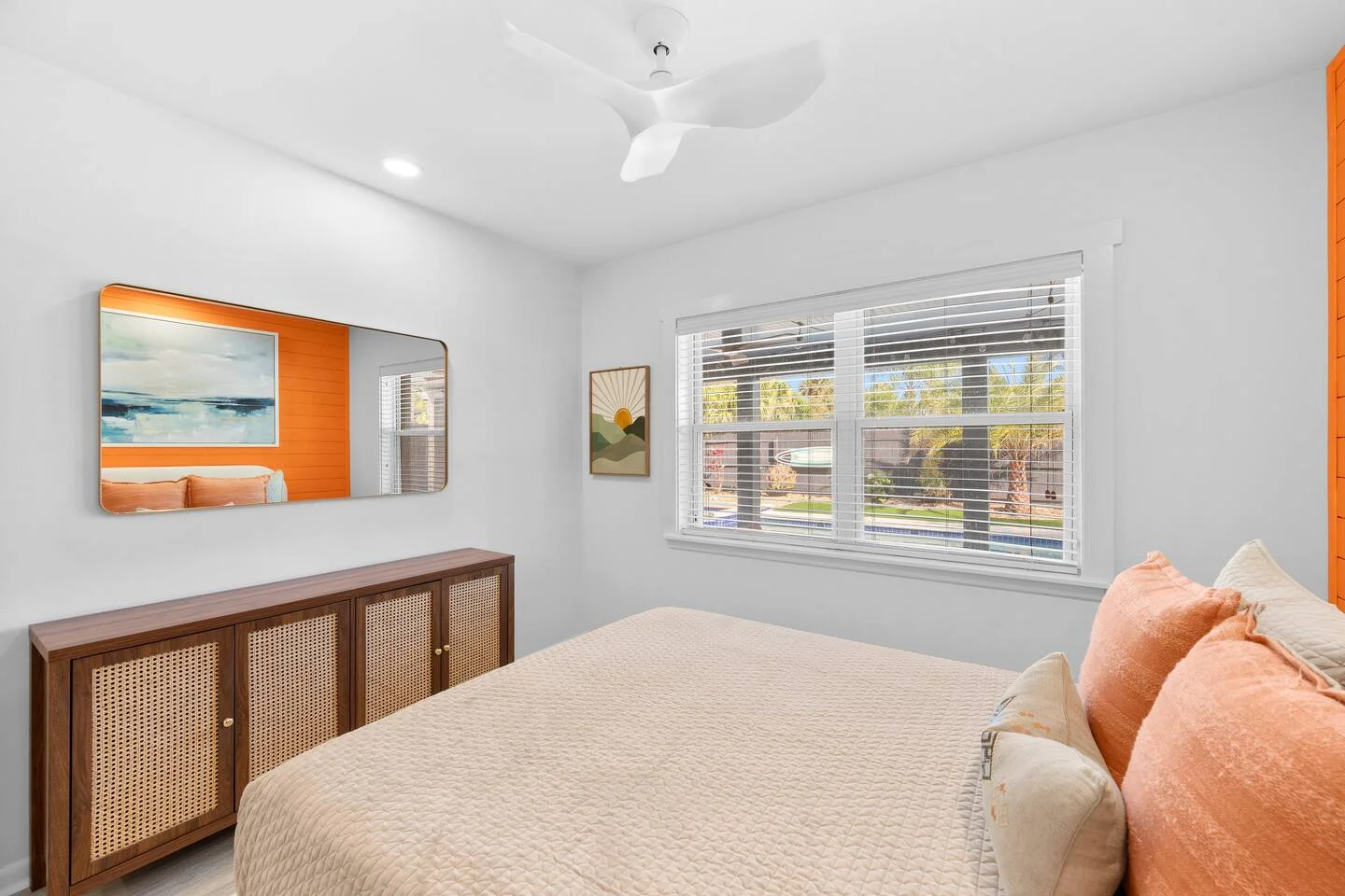 Modern St Augustine FL house rental bedroom with queen bed, cathedral ceilings, orange accent wall, and coastal decor