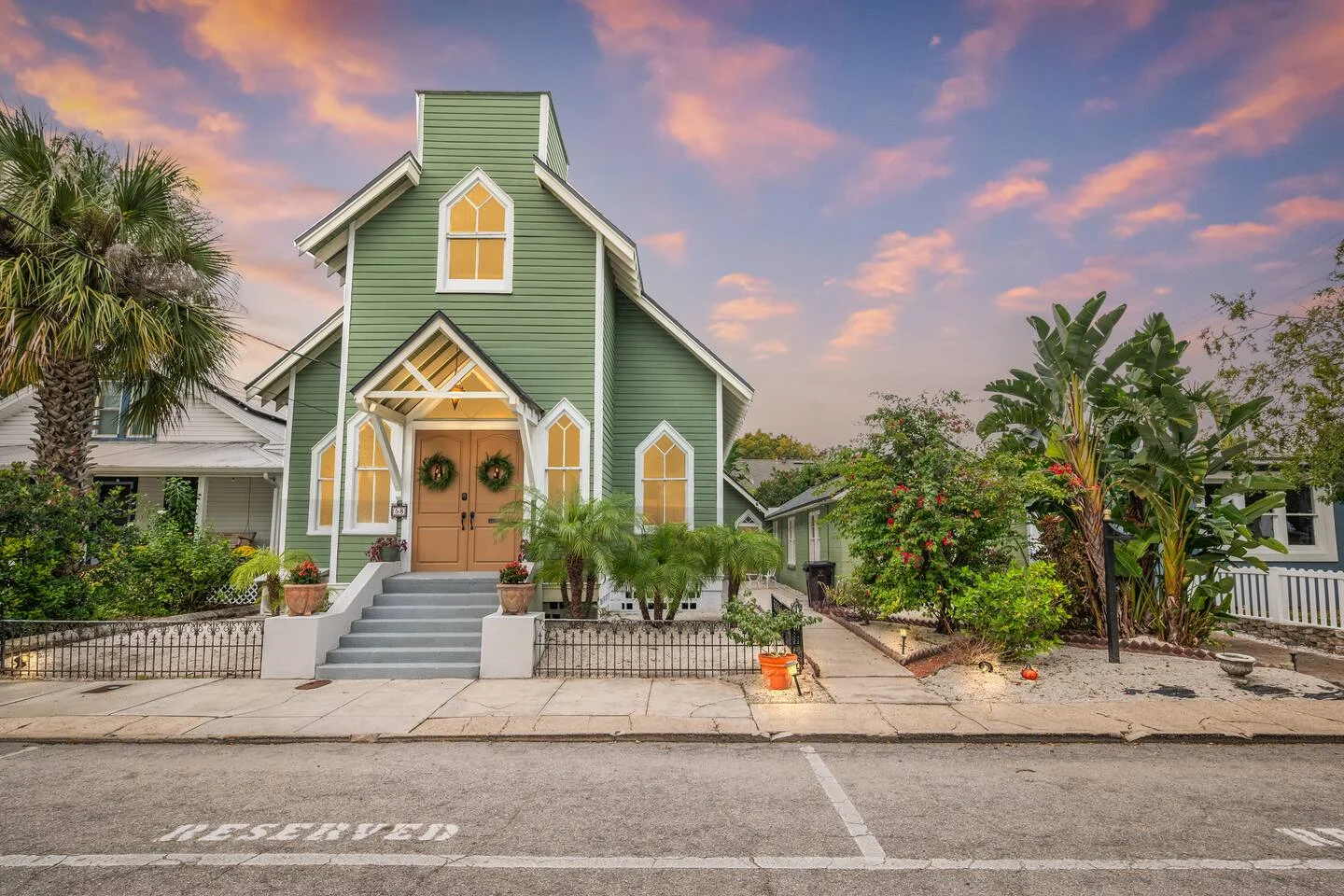 Historic green and white church cottage with arched windows and palm trees demonstrating property management investment in