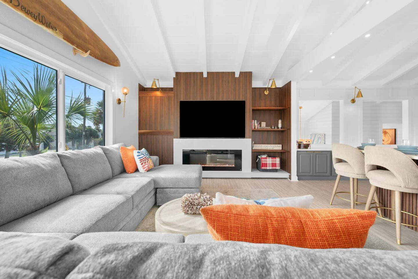 Modern living room in St Augustine FL single-family home with gray sectional, fireplace, and tropical palm tree views