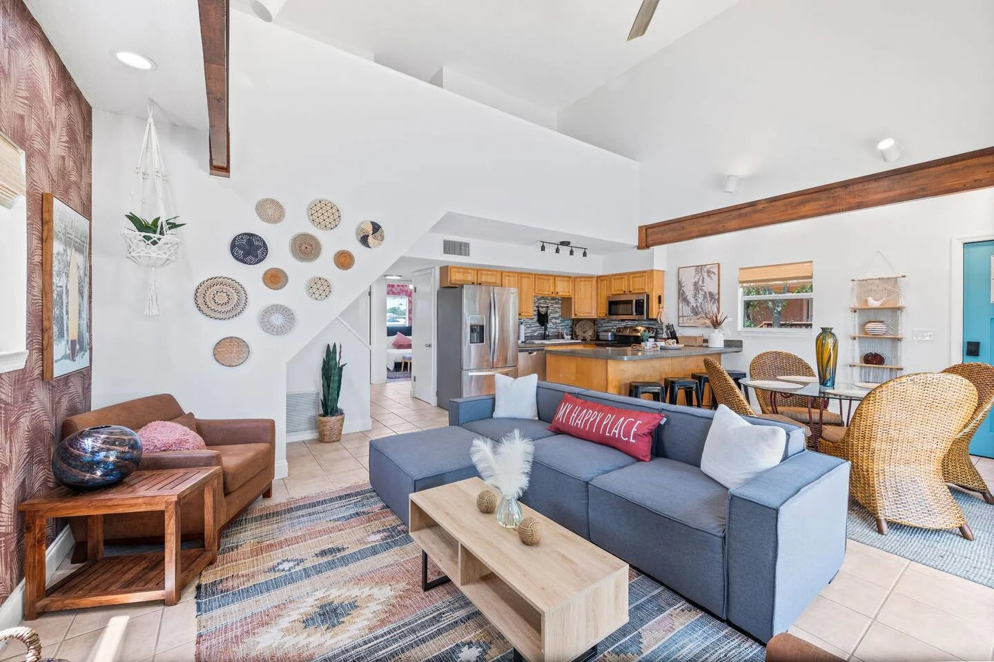 Open-concept coastal living room with blue sectional sofa and kitchen view, illustrating property layout considerations for