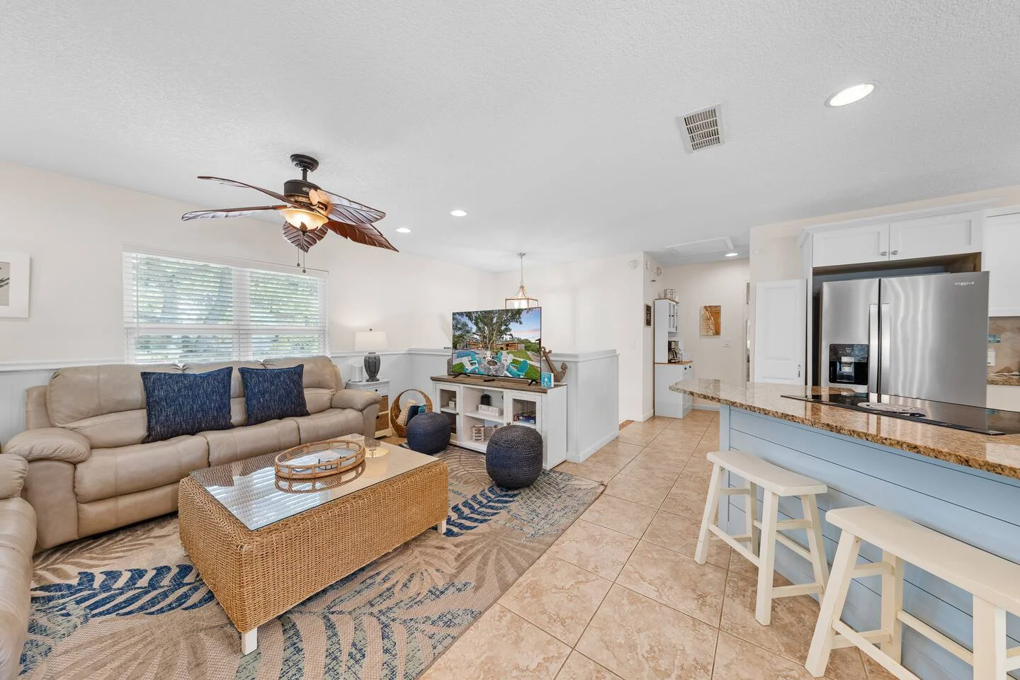Open-concept living room with beige sectional sofa and modern kitchen, showing vacation rental property management setup