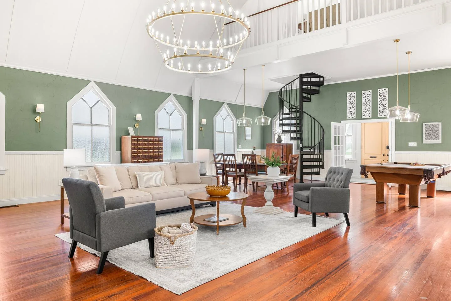 Luxury open-concept living room with sage green walls, hardwood floors, and modern chandelier representing high-value St.