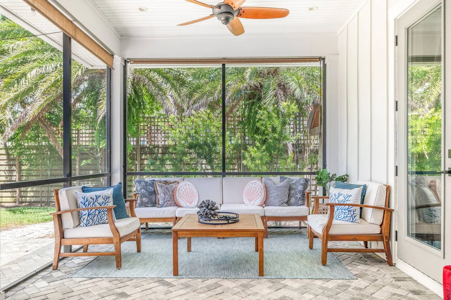 Coastal-themed covered patio with teak furniture and blue pillows showcasing vacation rental design trends for St. Augustine