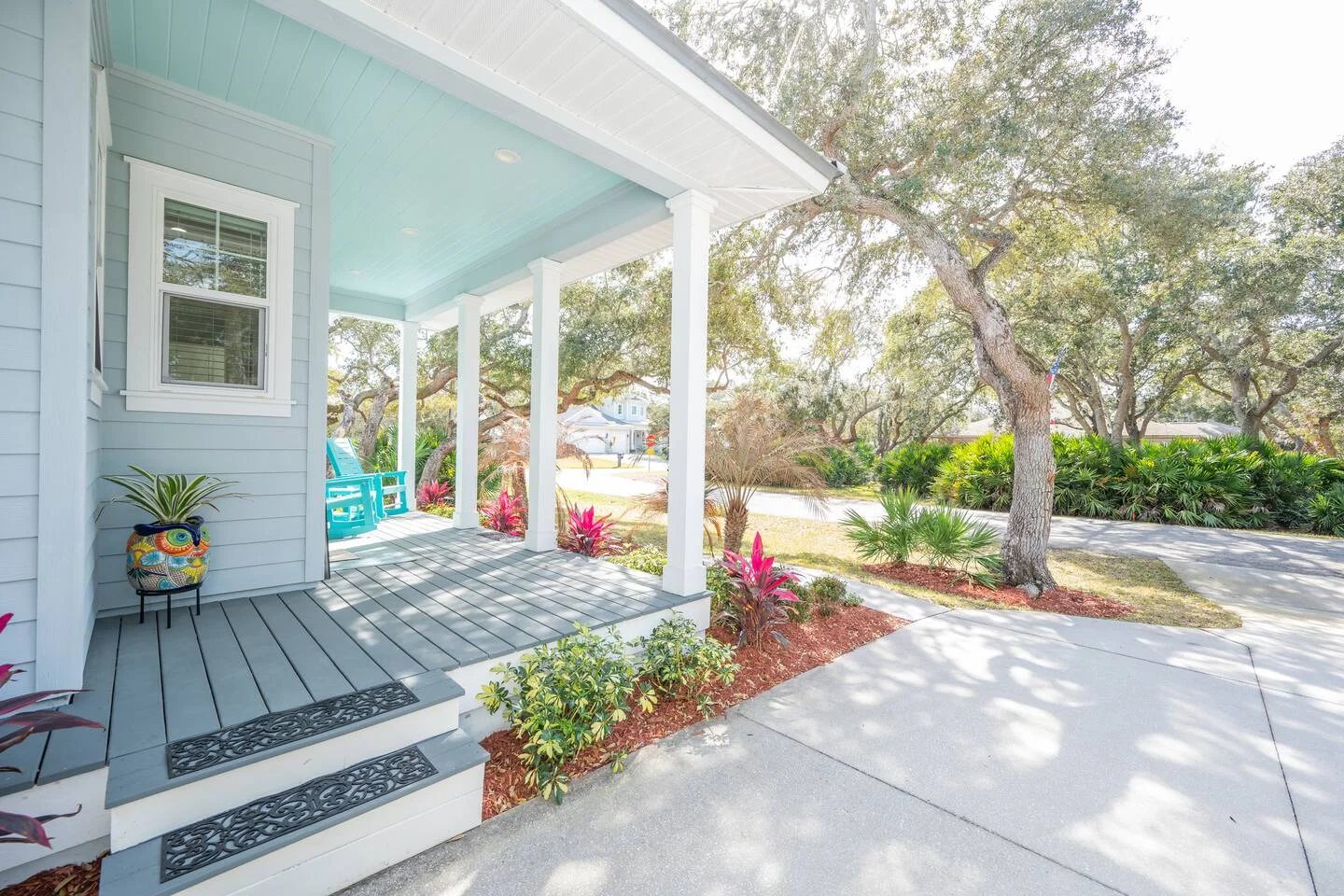 Modern coastal porch with turquoise Adirondack chairs and pale blue ceiling at historic homes for rent in St Augustine FL