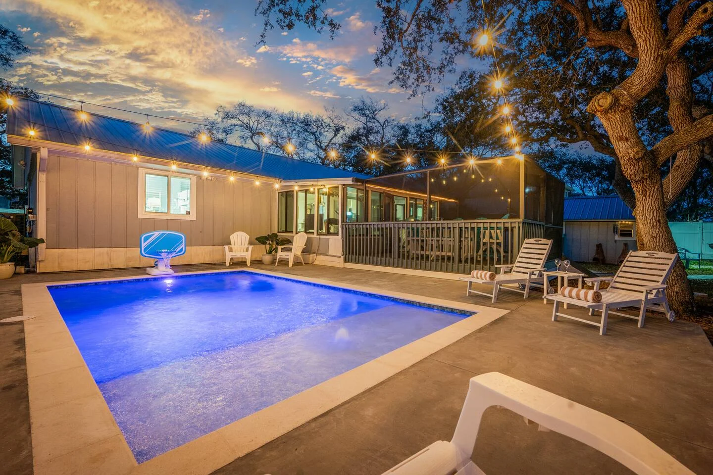 Resort-style backyard swimming pool with string lights and lounge chairs, illustrating luxury vacation rental amenities
