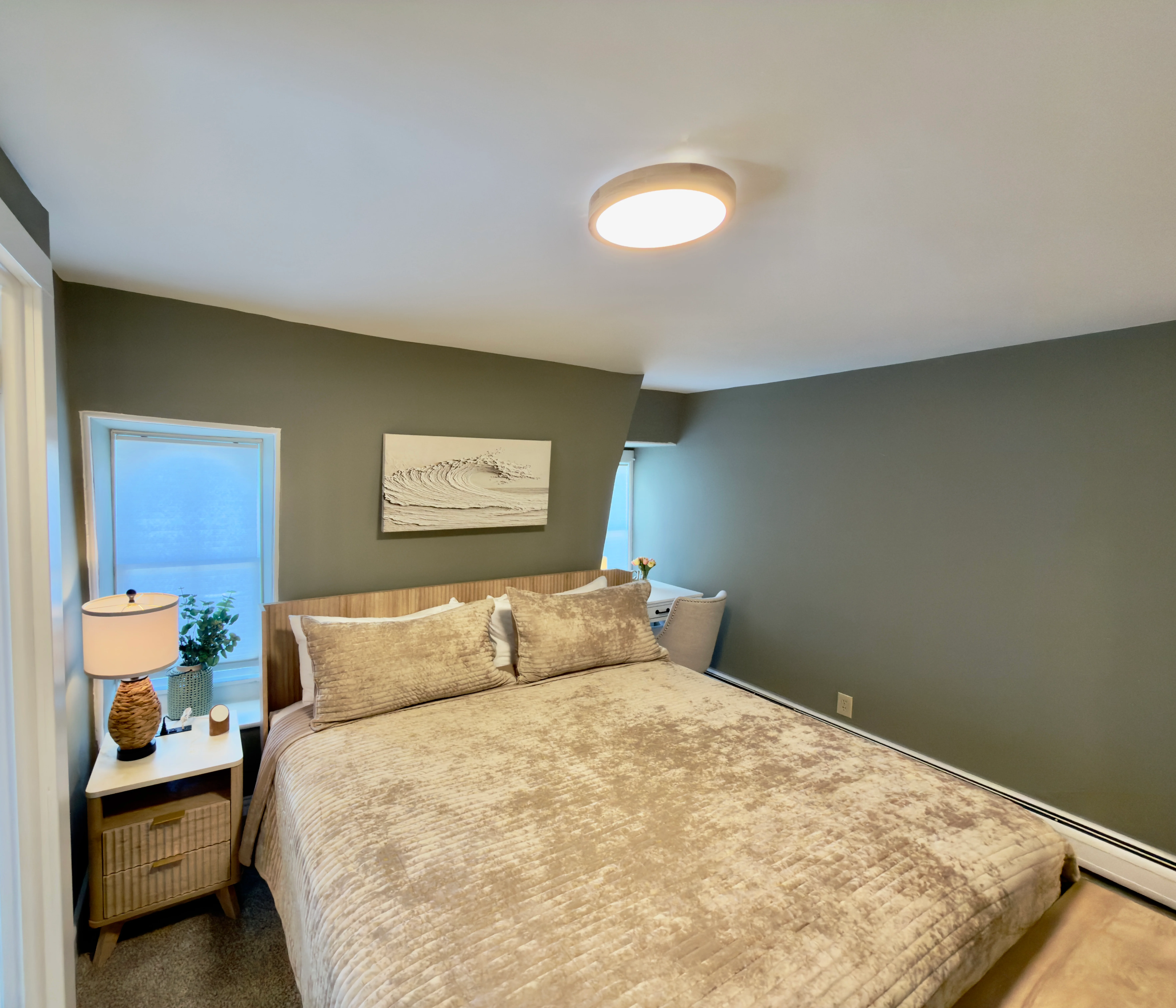 Modern coastal bedroom with sage green walls and ocean views, ideal for Cape May beach guide visitors