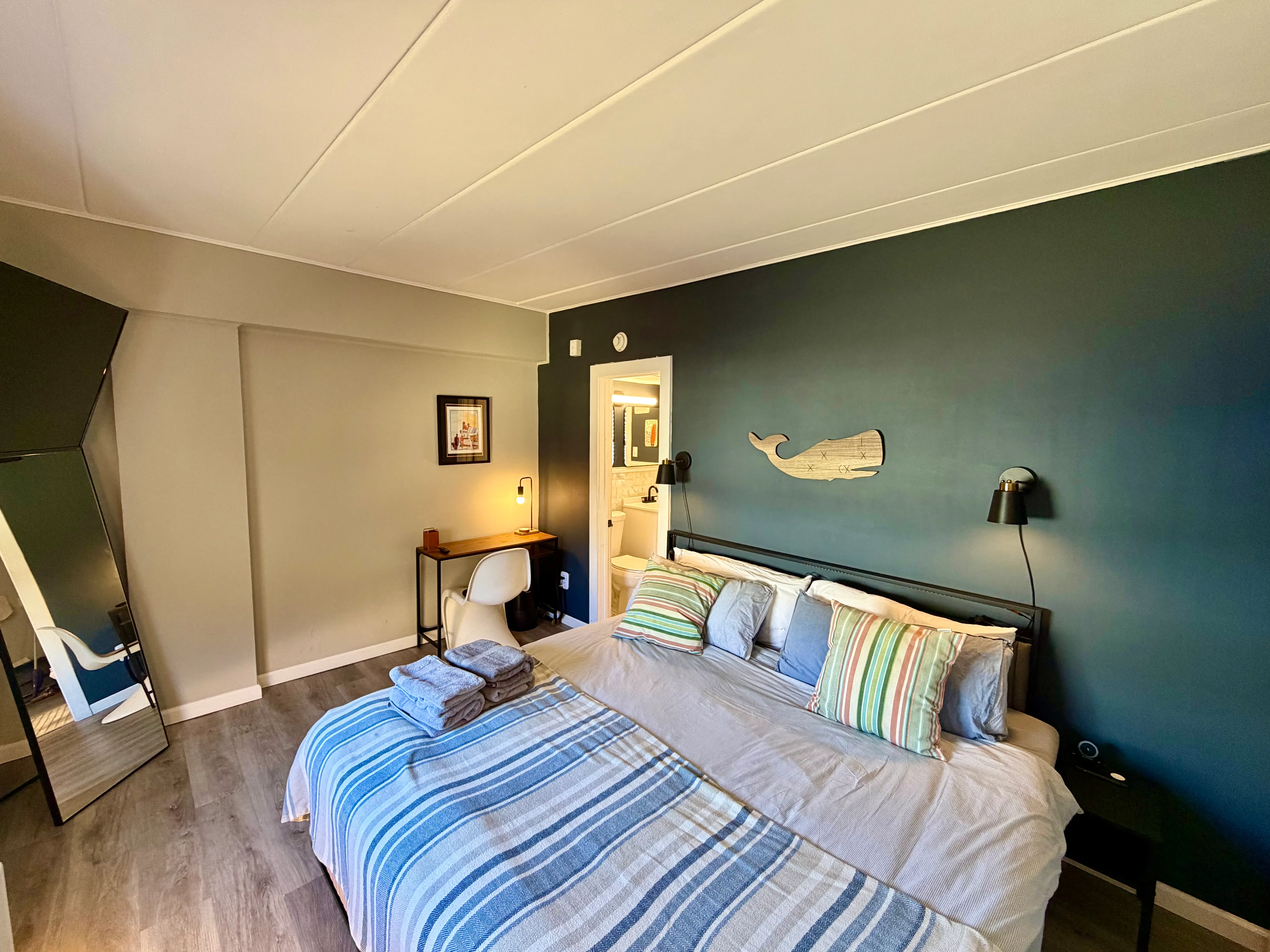 Modern master bedroom with teal accent wall and nautical whale decor in Cape May Victorian historic district property