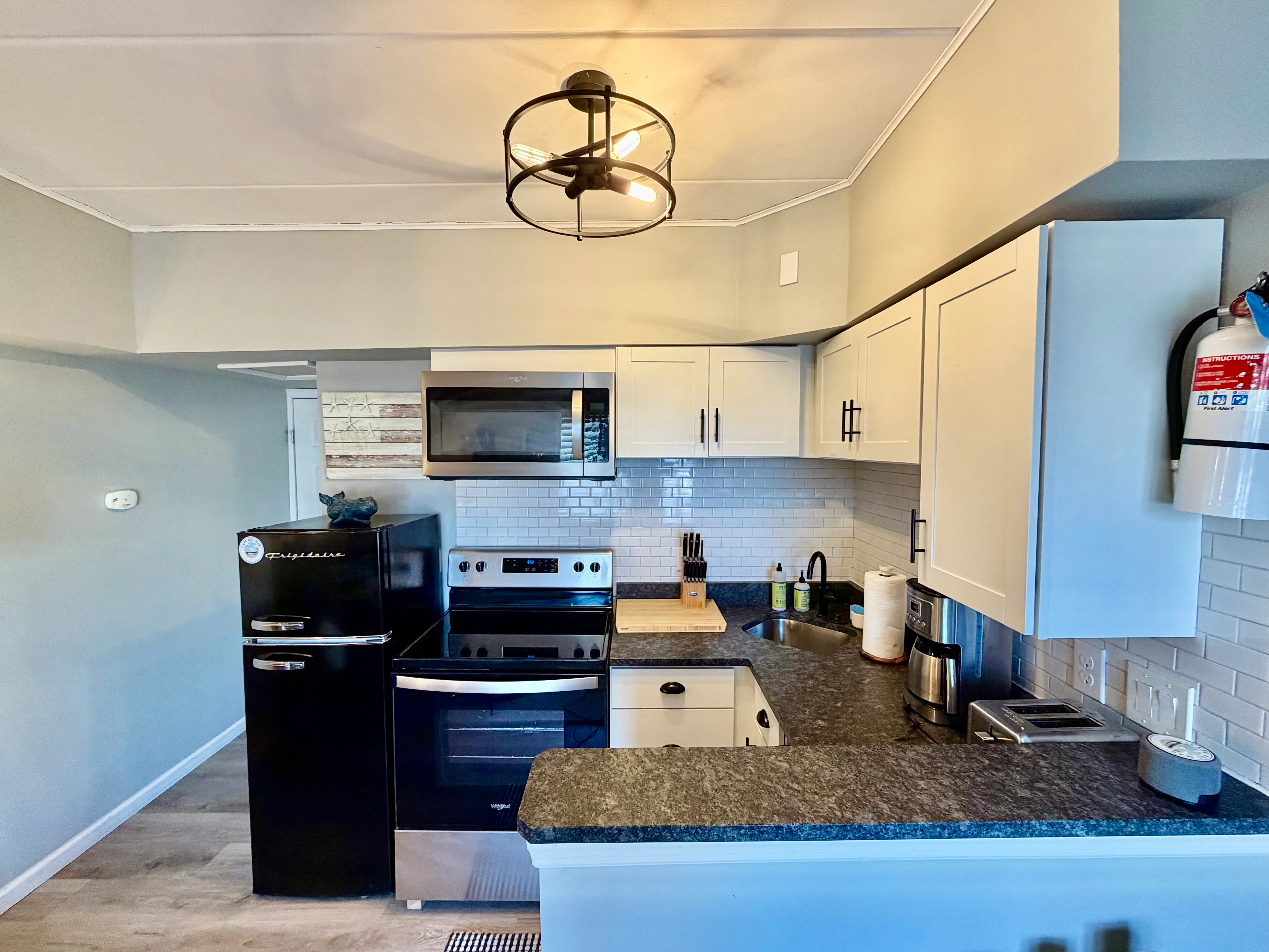 Modern kitchen with black stainless steel appliances, white subway tile backsplash, and granite countertops at Cape Whale