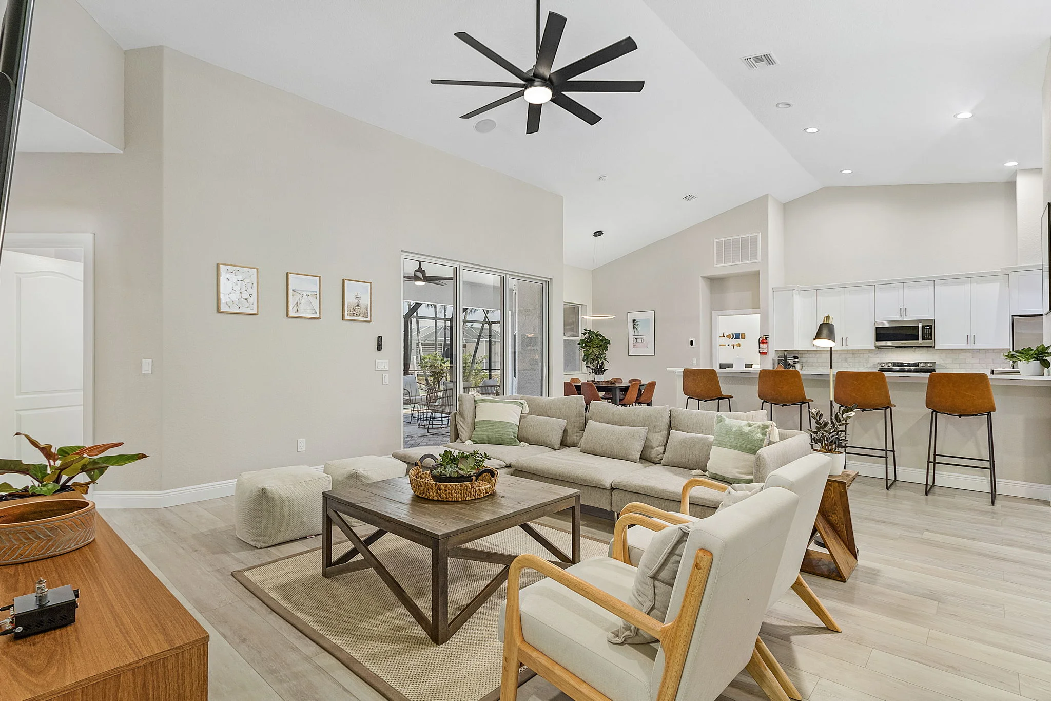 Modern open-concept kitchen and dining area with cream and black cabinetry, stainless steel appliances, and black countertop