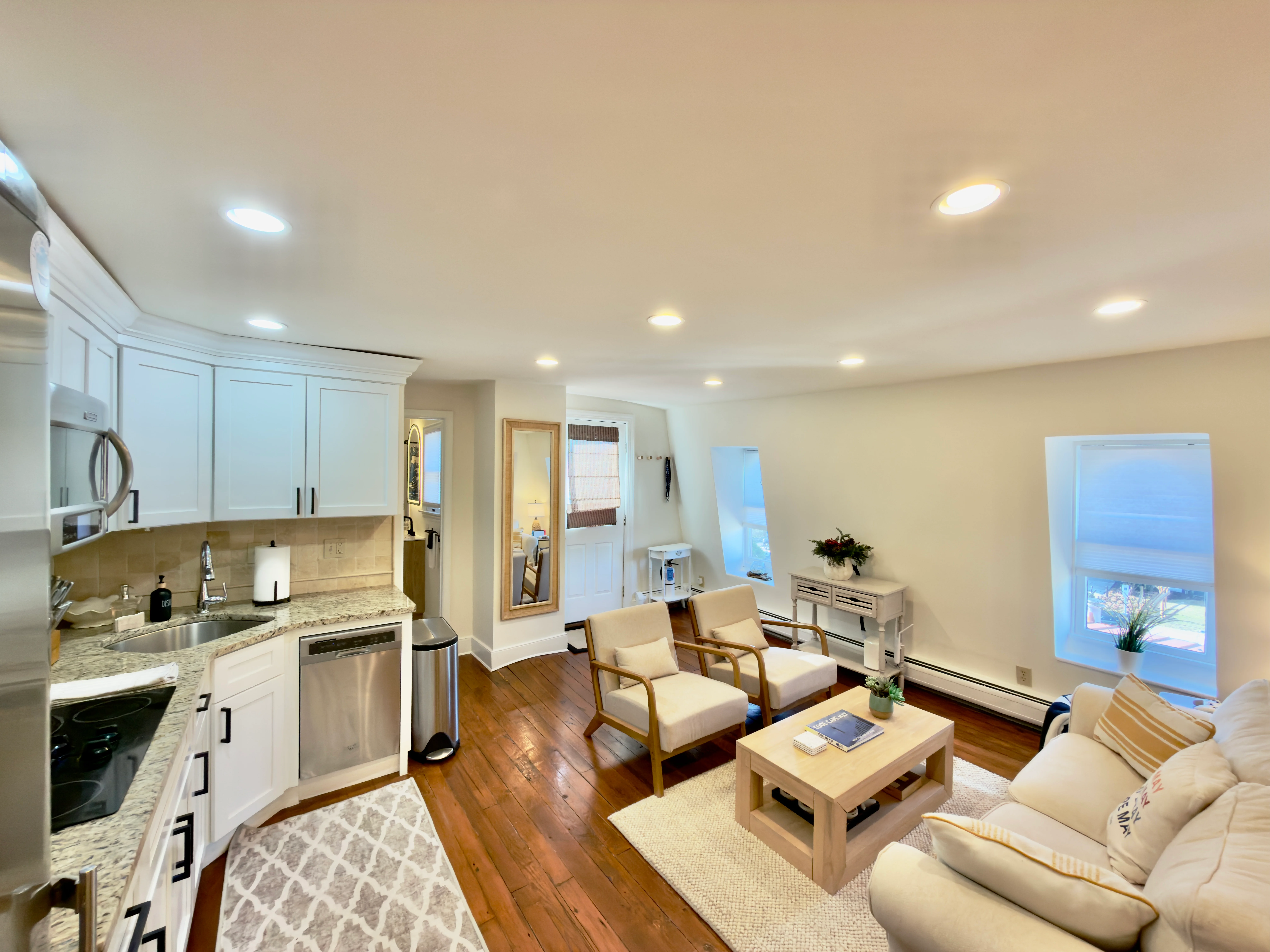 Modern open-concept living room and kitchen with white cabinetry and granite countertops at Cape Wave property in Cape May NJ