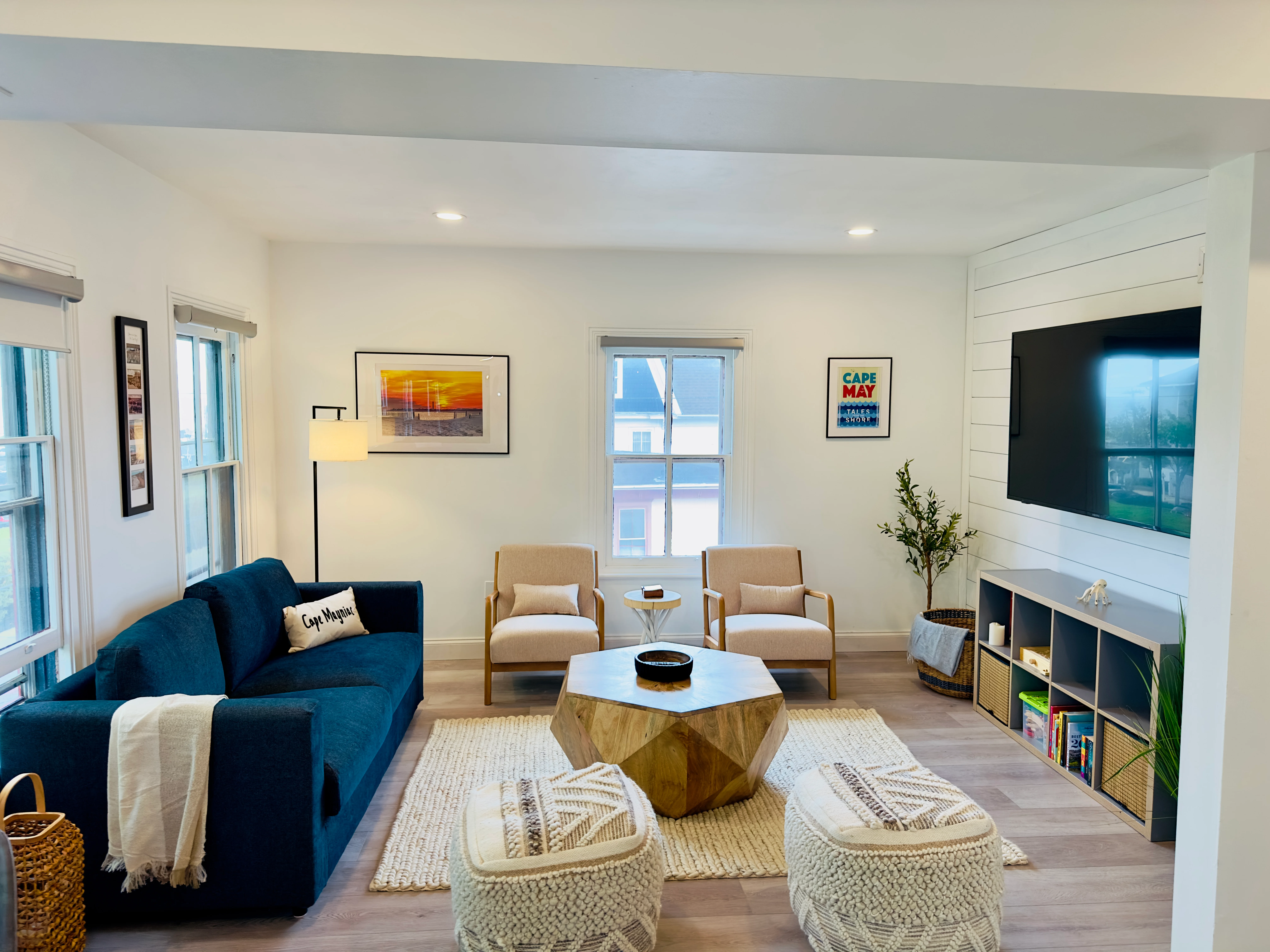 Bright living room with cream walls, hardwood floors, and large windows in a Cape May New Jersey vacation rental featuring