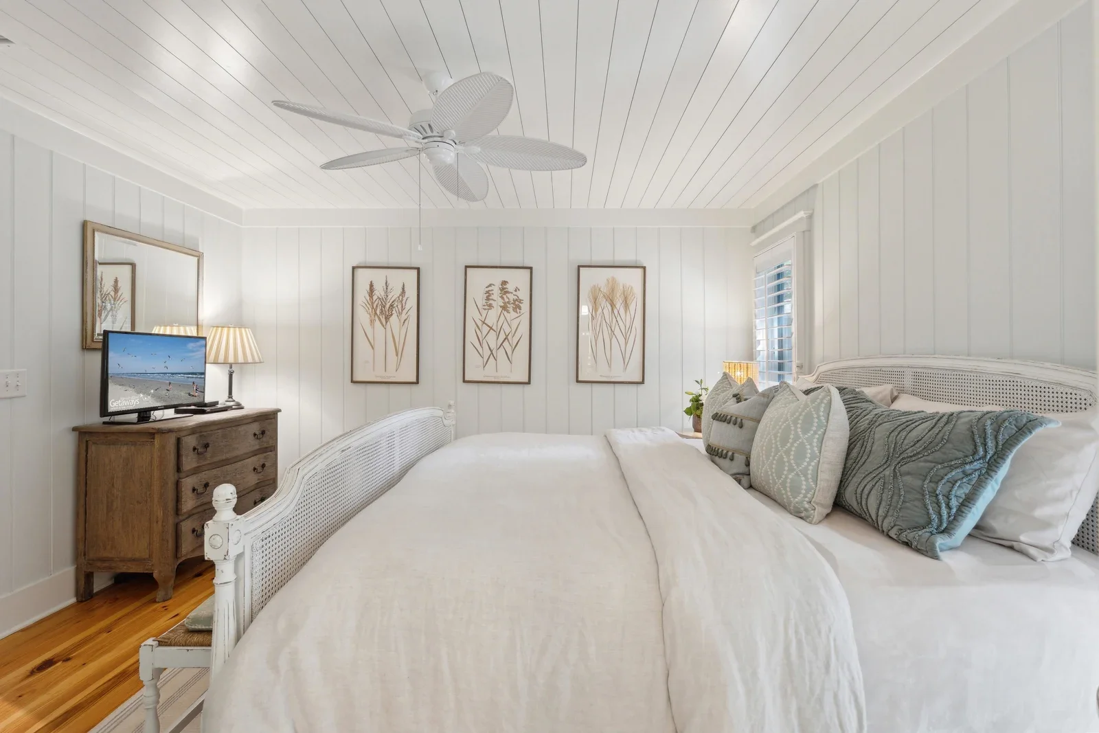 Bright coastal bedroom with white shiplap, queen beds, and botanical art at Kiawah Island private home