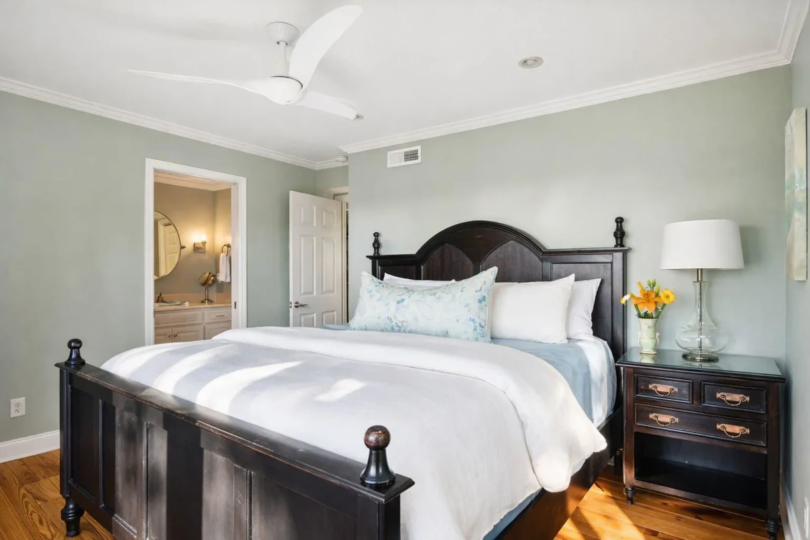 Coastal bedroom with sage green walls, black iron bed, white trim in Kiawah Island oceanfront home