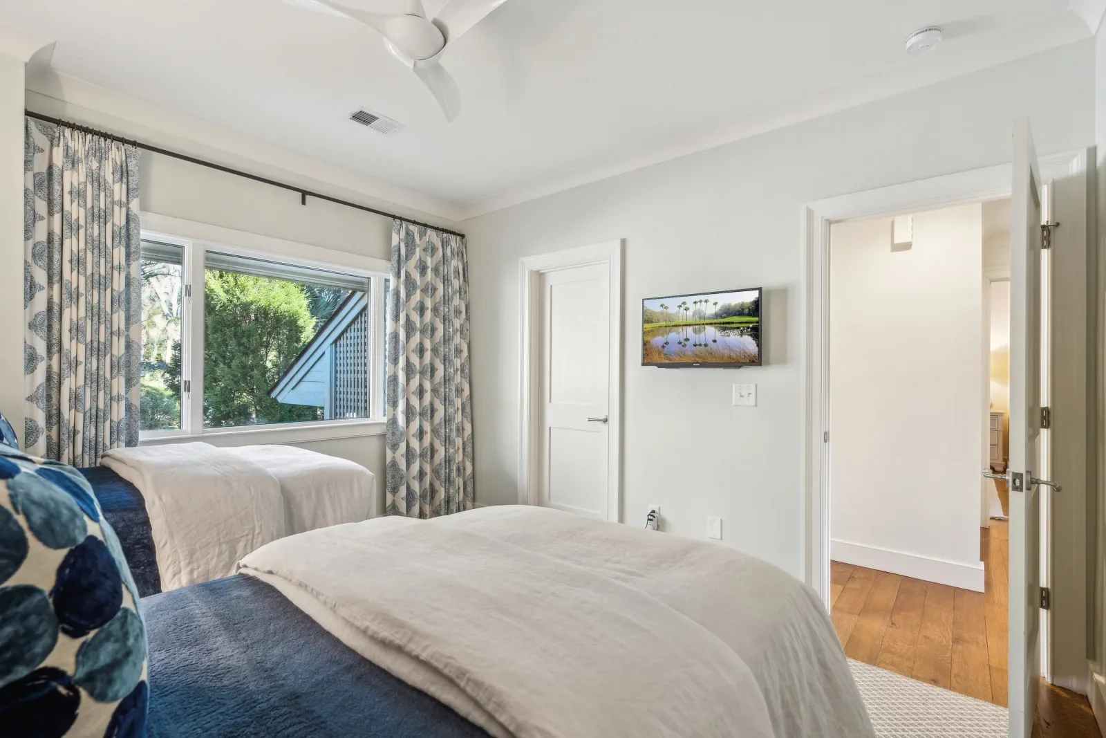 Coastal guest bedroom with two queen beds and ocean view window at Kiawah Island rental villa