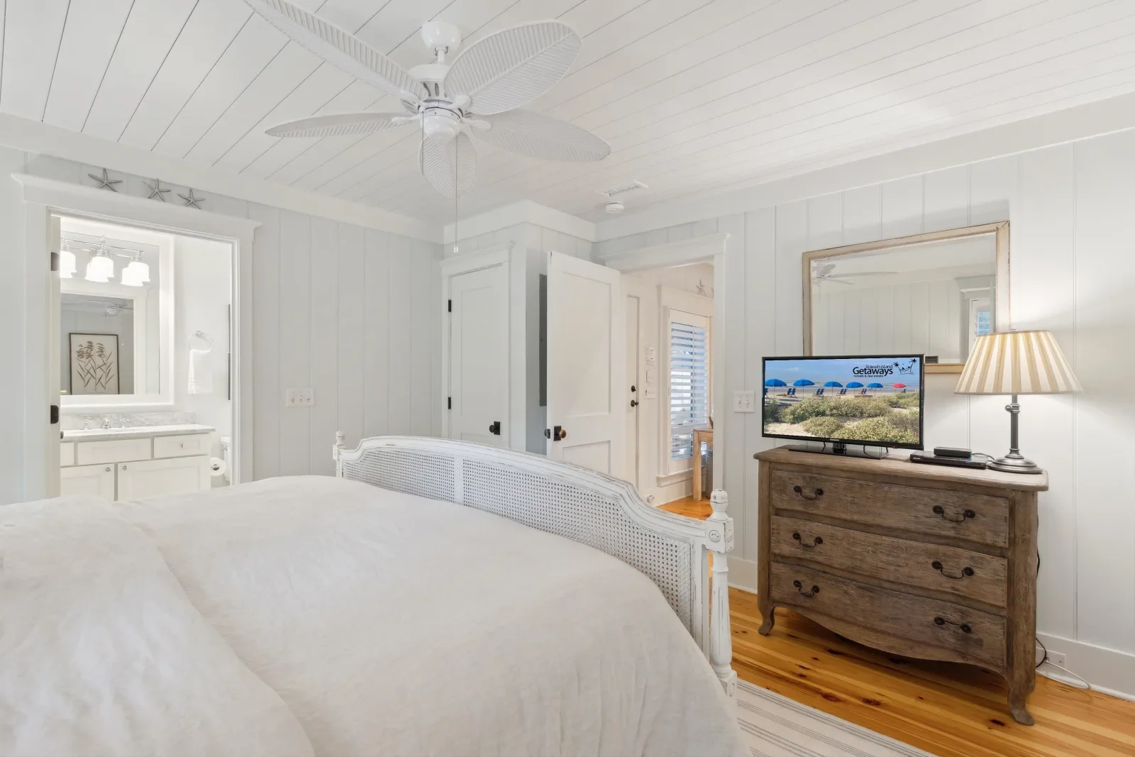 Sparrow Pond cottage Kiawah Island master bedroom with white metal bed hardwood floors and coastal decor