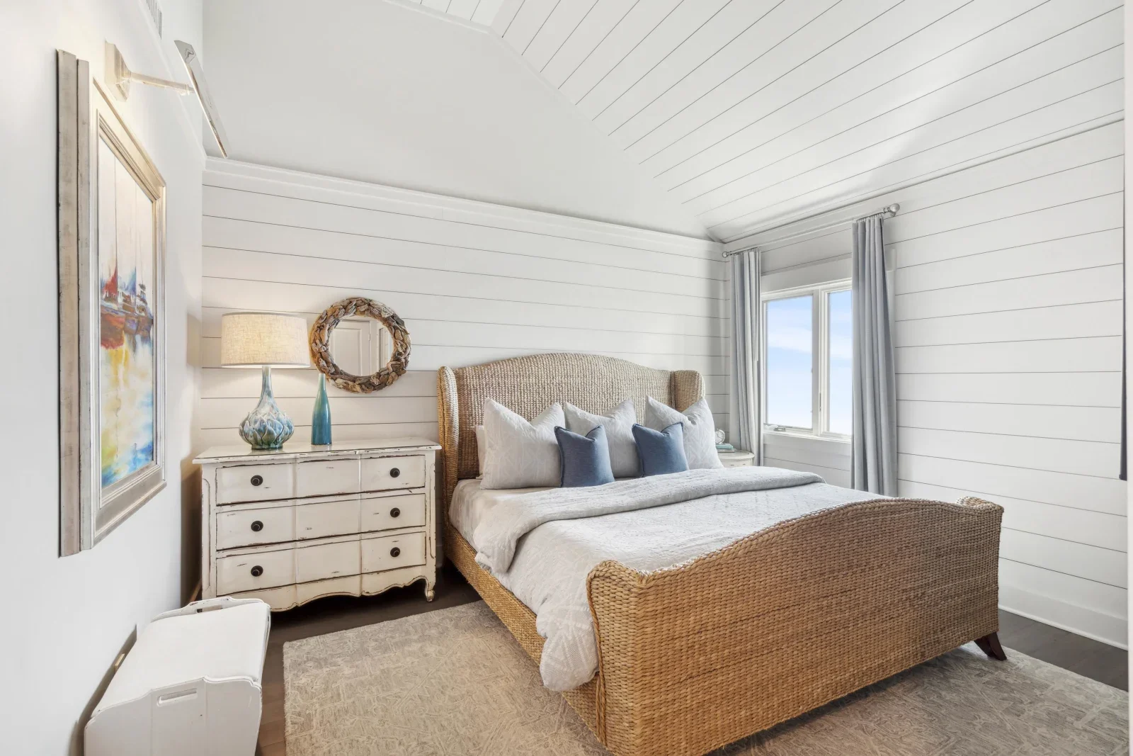 Coastal master bedroom with rattan bed and shiplap walls in Kiawah Island summer rental