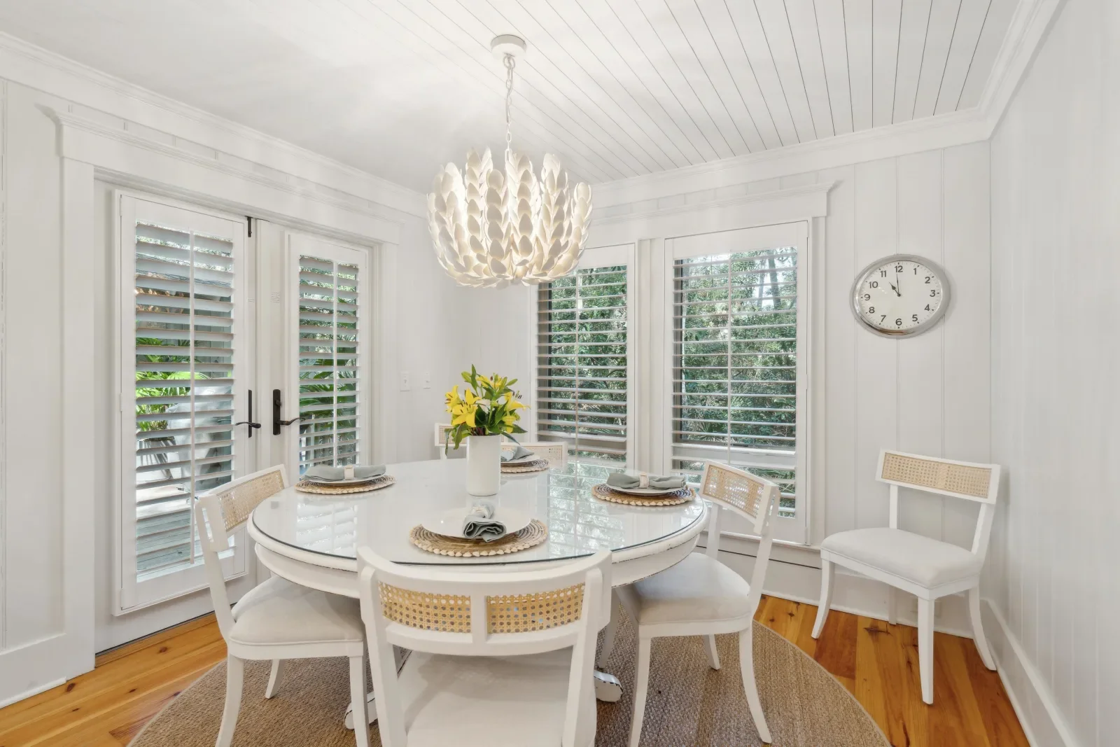Coastal screened porch dining setup with round white table and shuttered windows at luxury Kiawah Island beach house
