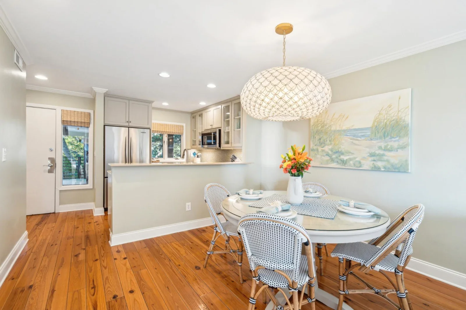 Coastal kitchen and dining area with cream cabinetry, hardwood floors, and pendant lighting on Kiawah Island